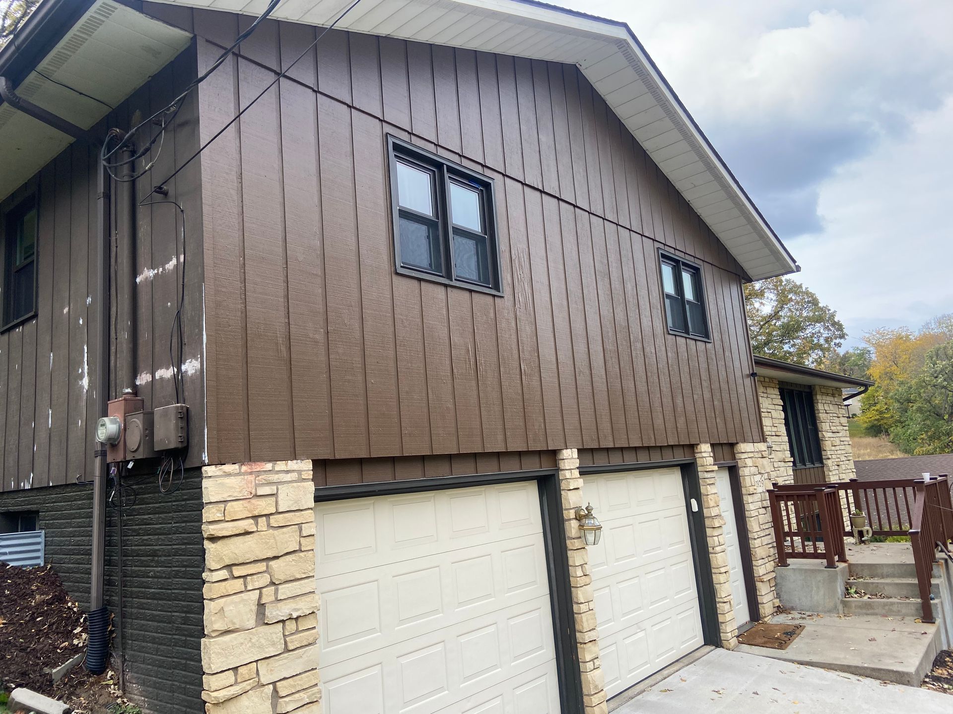 A brown house with two garage doors and two windows.