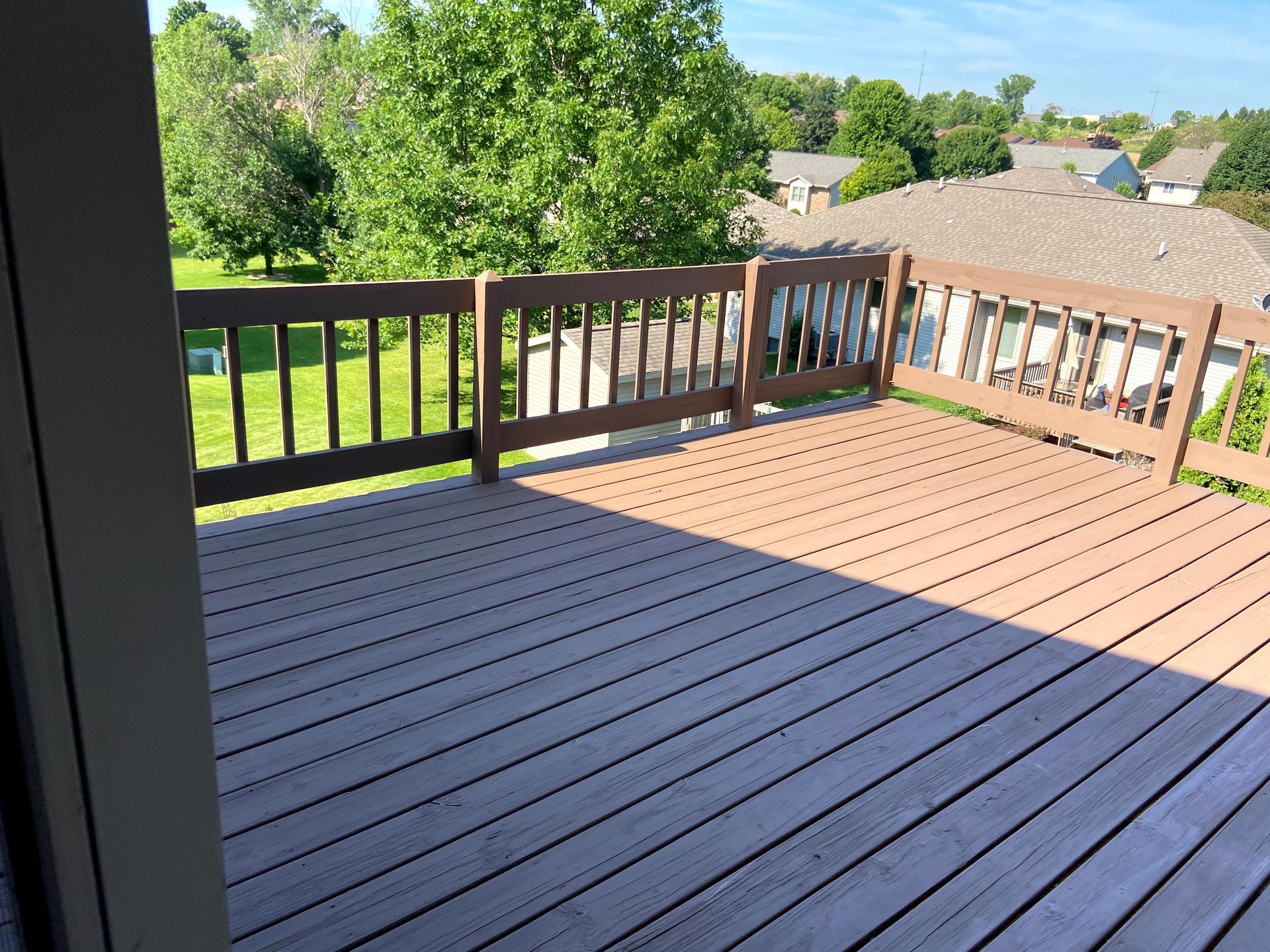 An empty deck with a railing and a view of a residential area.