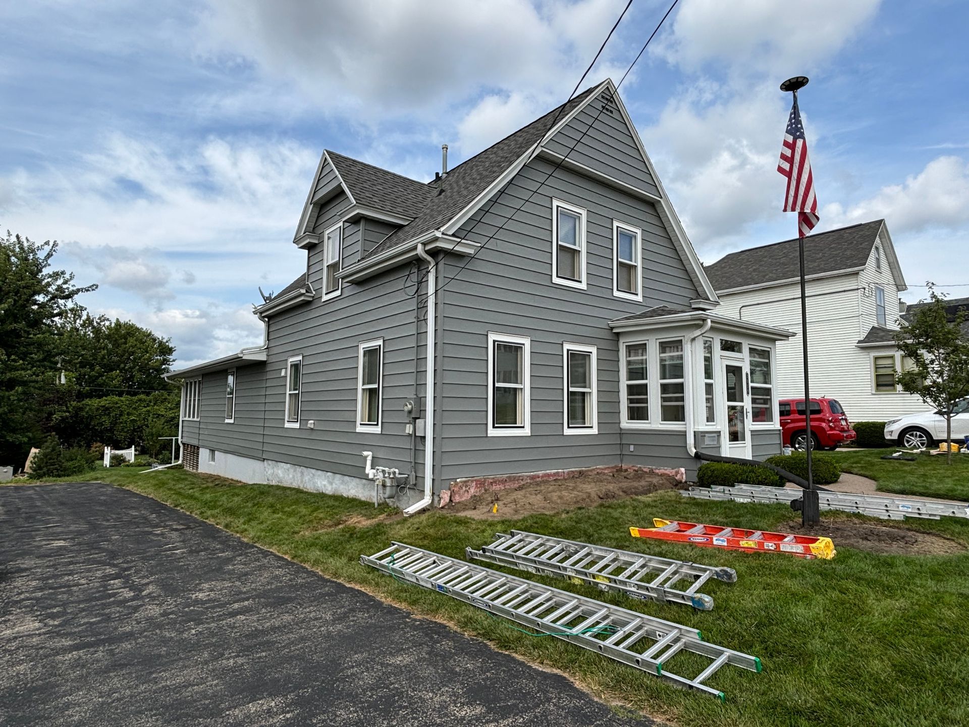A large gray house with a red truck parked in front of it.