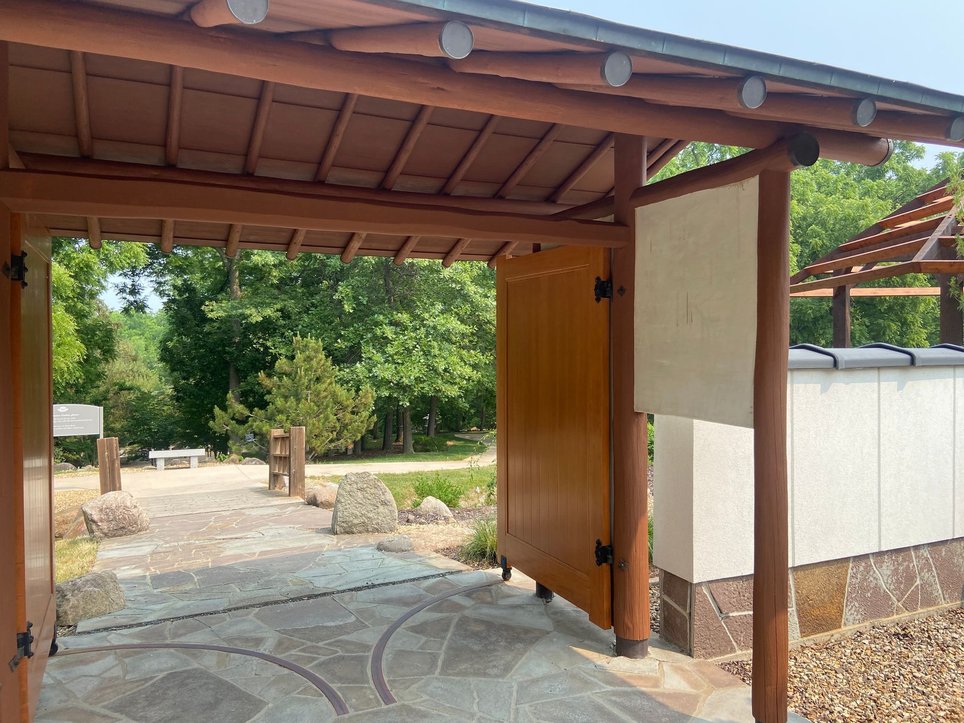 A wooden gate is open to a stone walkway.