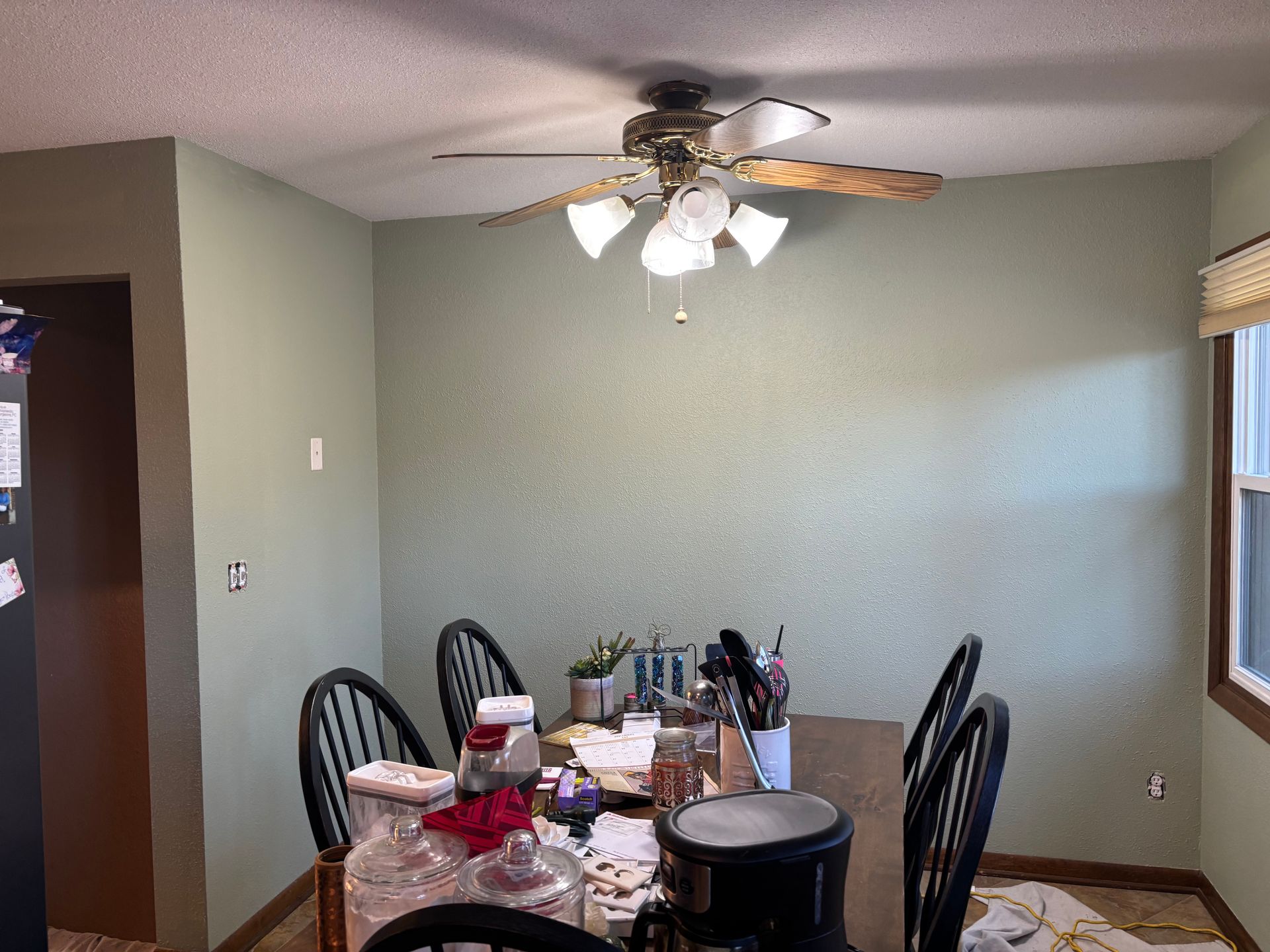 A dining room with a table and chairs and a ceiling fan.
