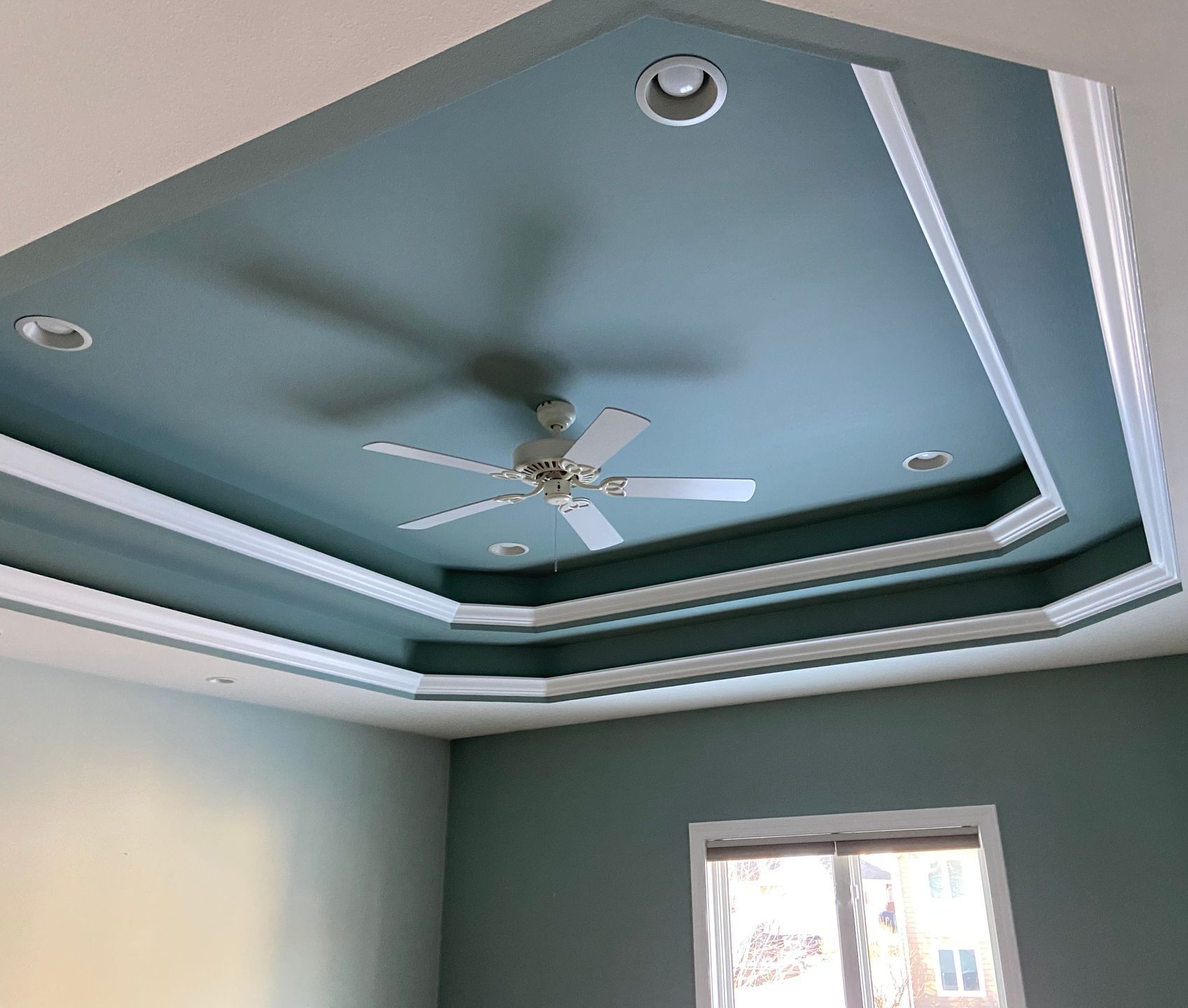 A room with a ceiling fan and a window