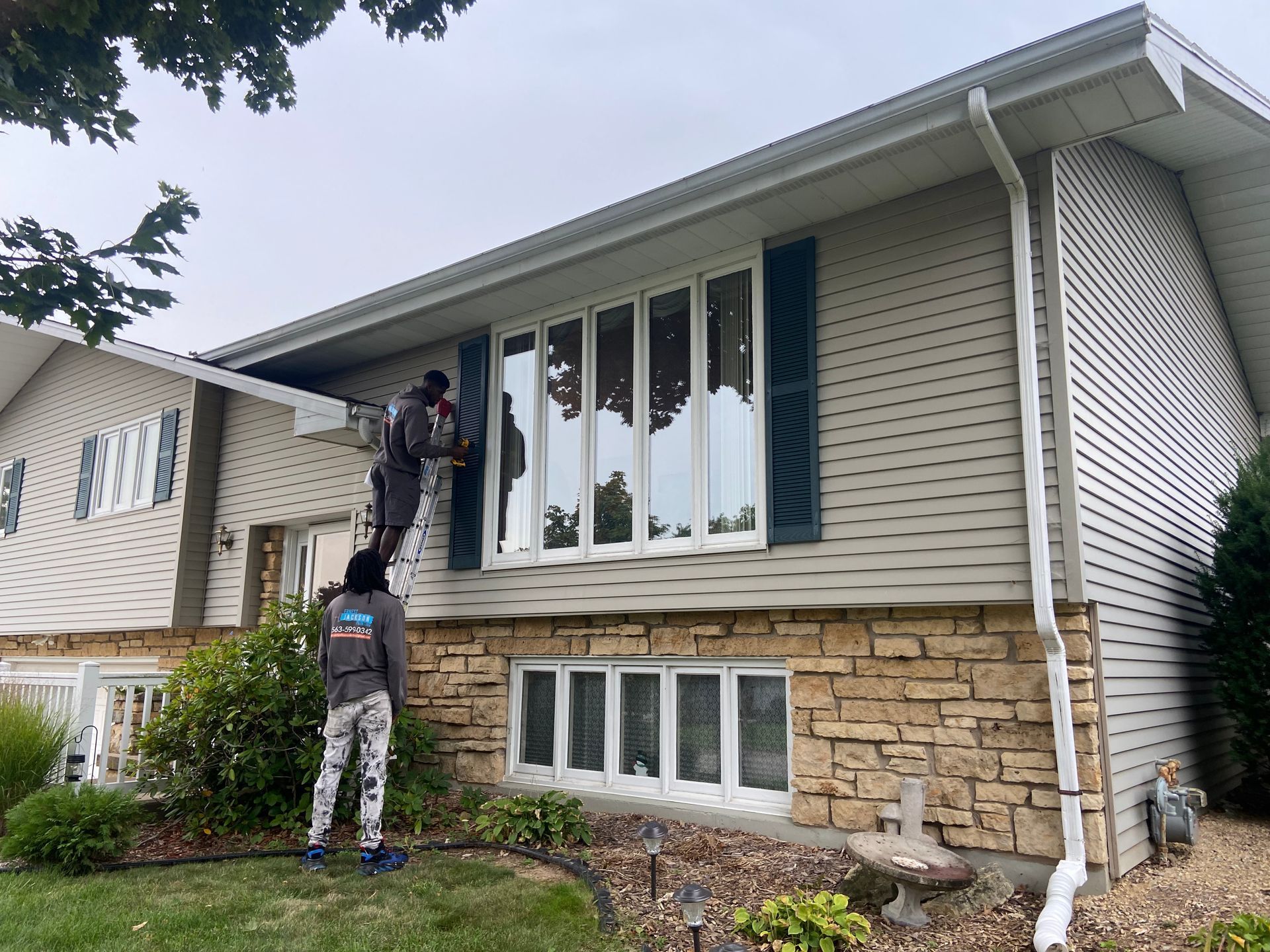 A group of people are painting the side of a house.