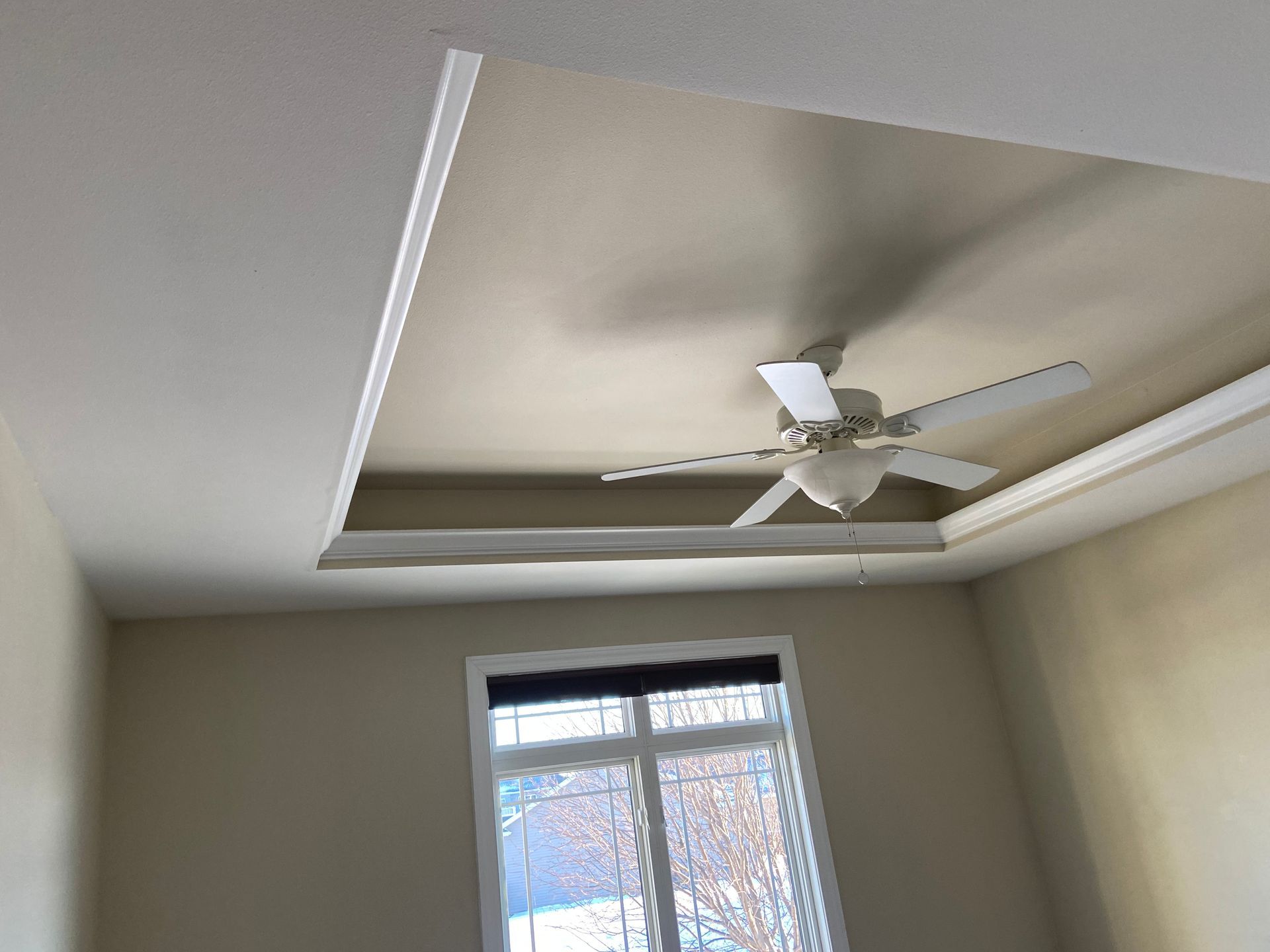A bedroom with a ceiling fan and a window