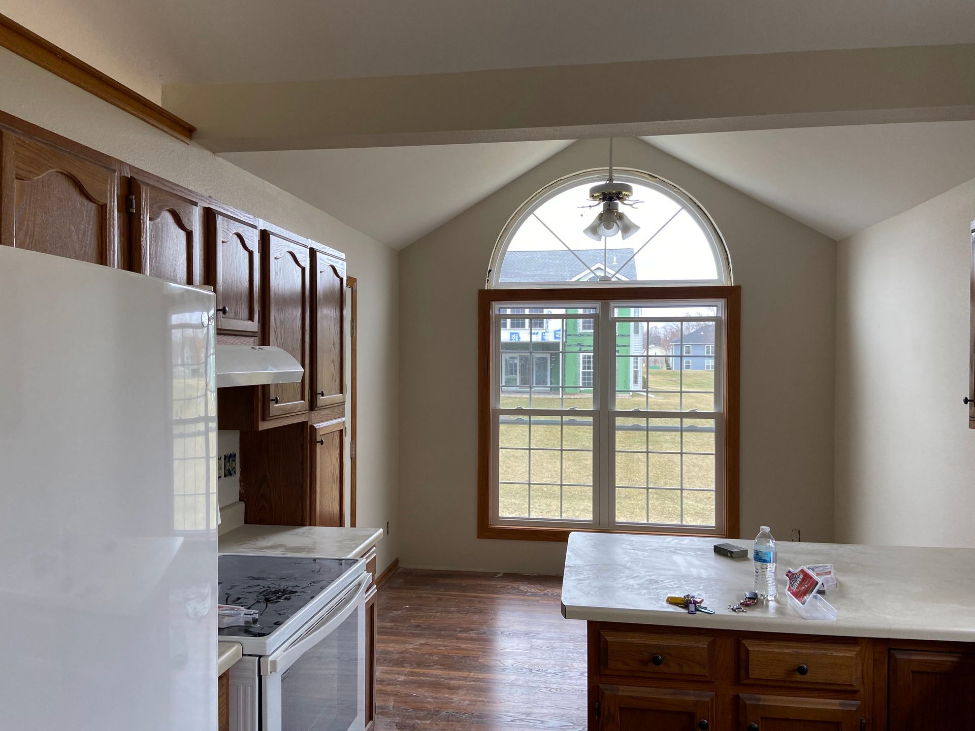 A kitchen with a stove , refrigerator , cabinets and a large window.