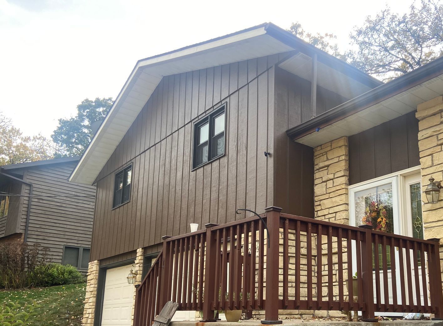 A house with a brown siding and a wooden deck.