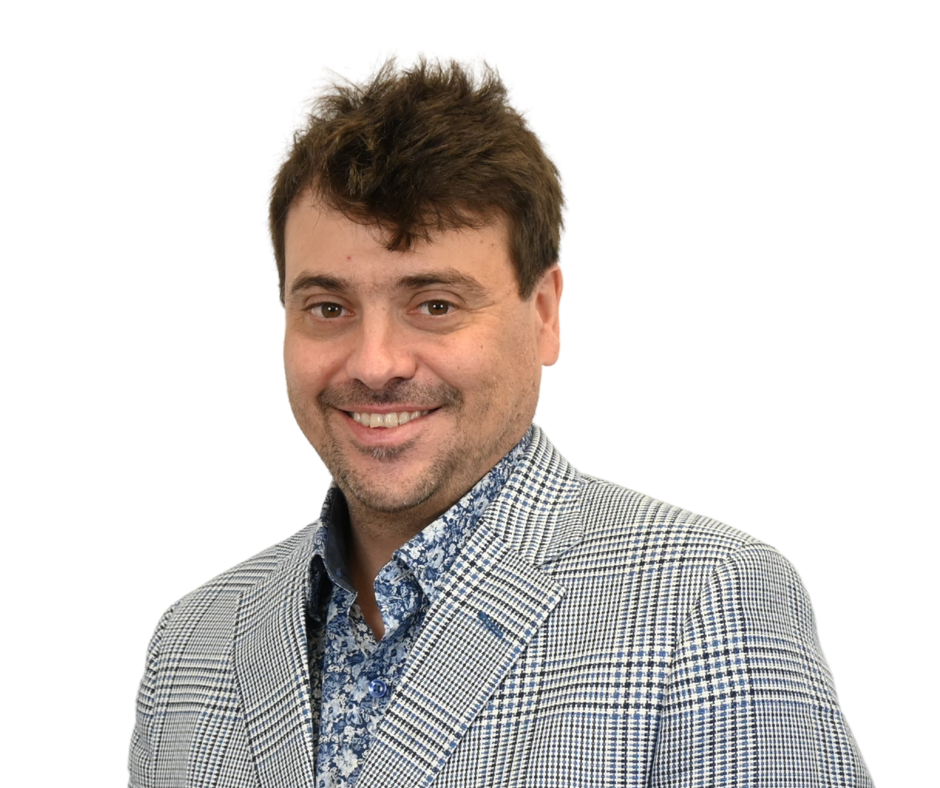Man with brown hair, smiling, wearing blue patterned shirt and checkered blazer.