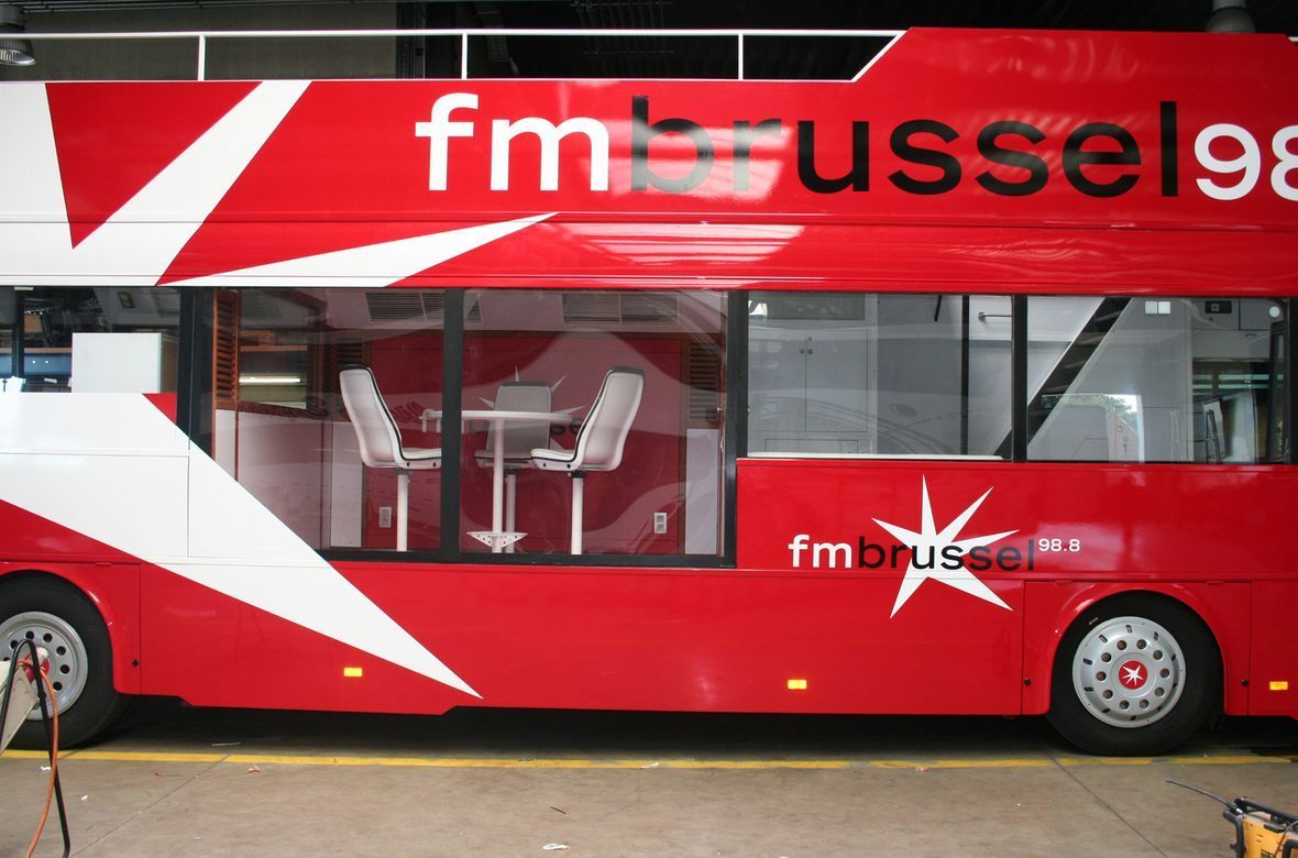Een rode bus met een wit en rood ontwerp, genaamd Feestbus FM Brussels.