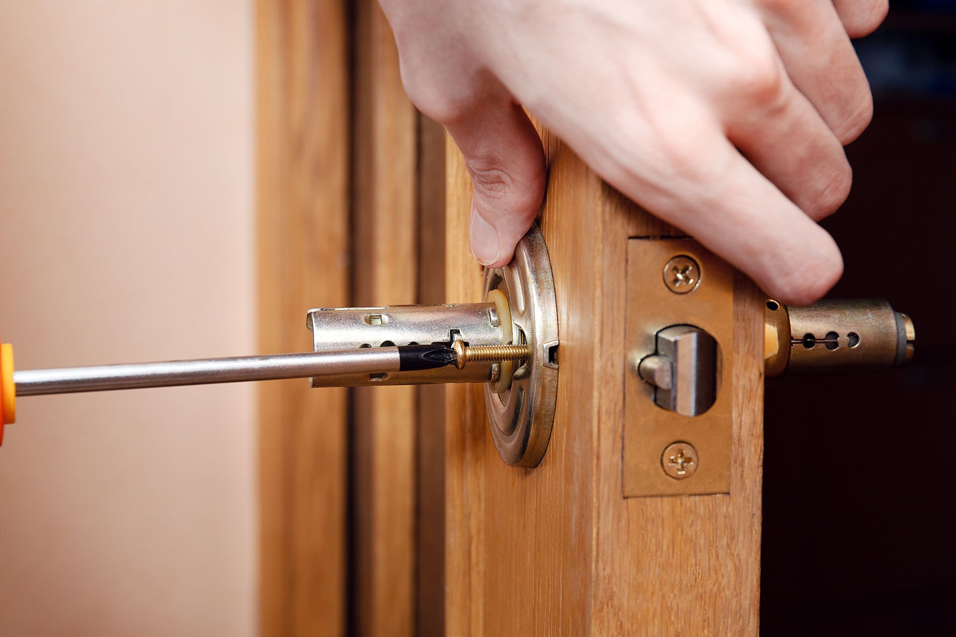 Close-up of a locksmith installing or repairing a door lock mechanism with a screwdriver.