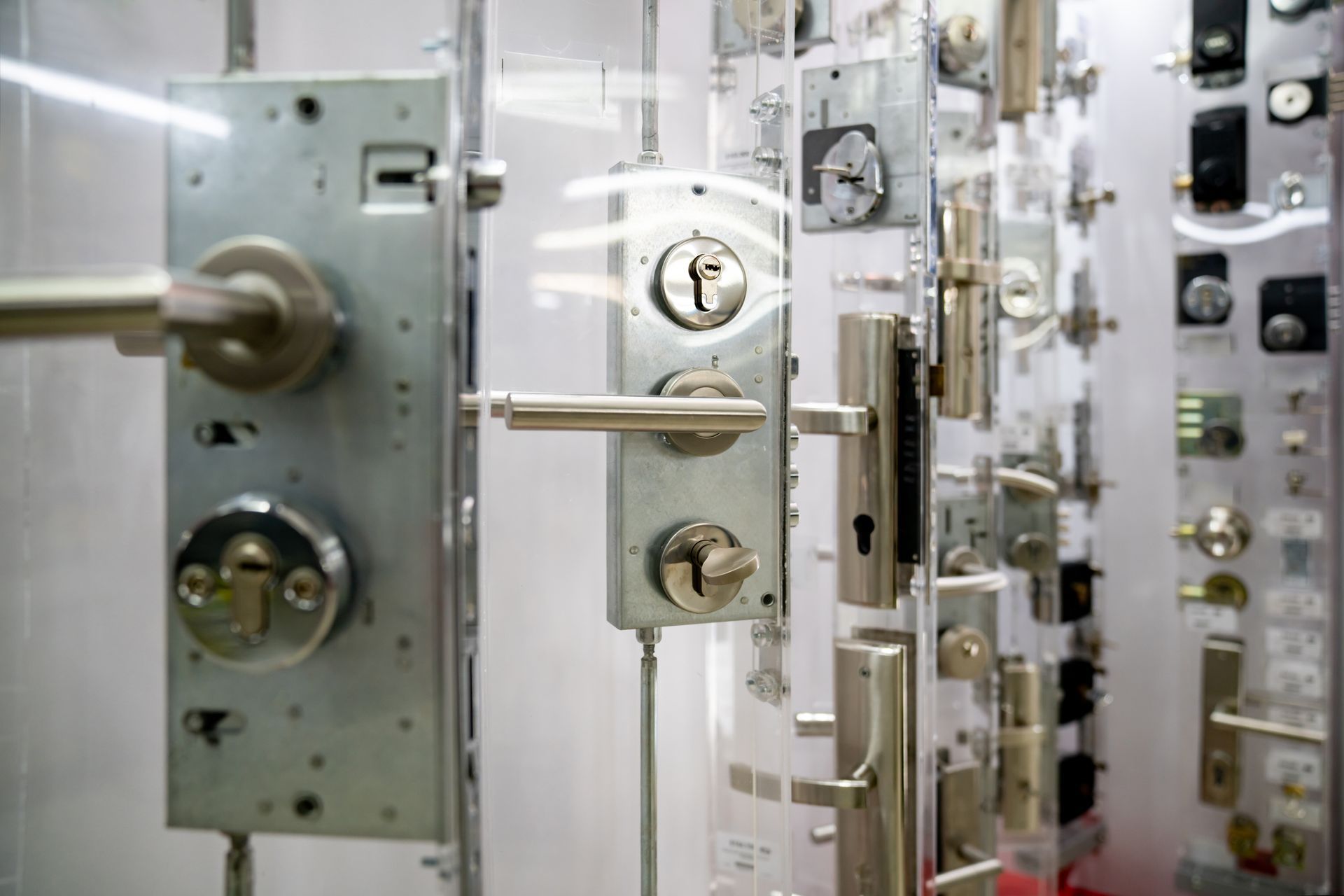 Close-up of a display case showcasing various silver-colored door locks and handles.