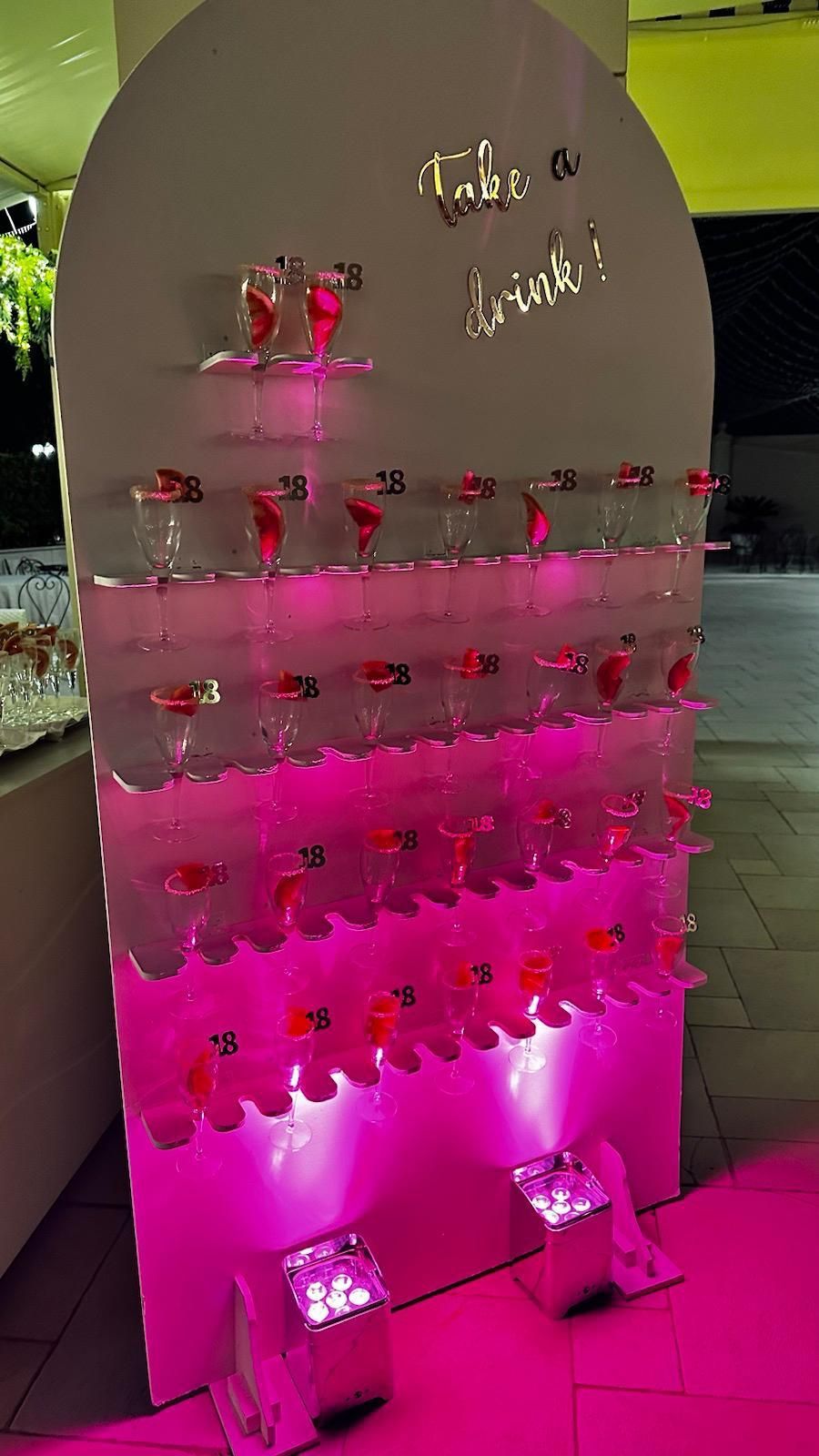 Una parete piena di bicchieri da vino e un cartello che dice ``prendi un drink''.