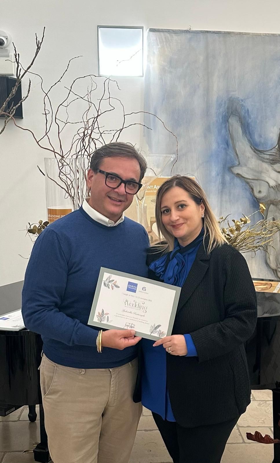 Un uomo e una donna sono in piedi uno accanto all'altro e tengono in mano un certificato.