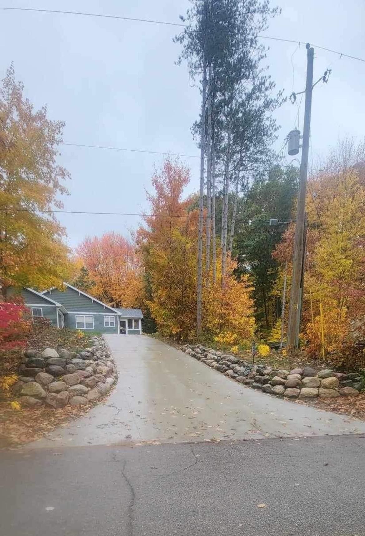 A driveway leading to a house surrounded by trees in autumn.