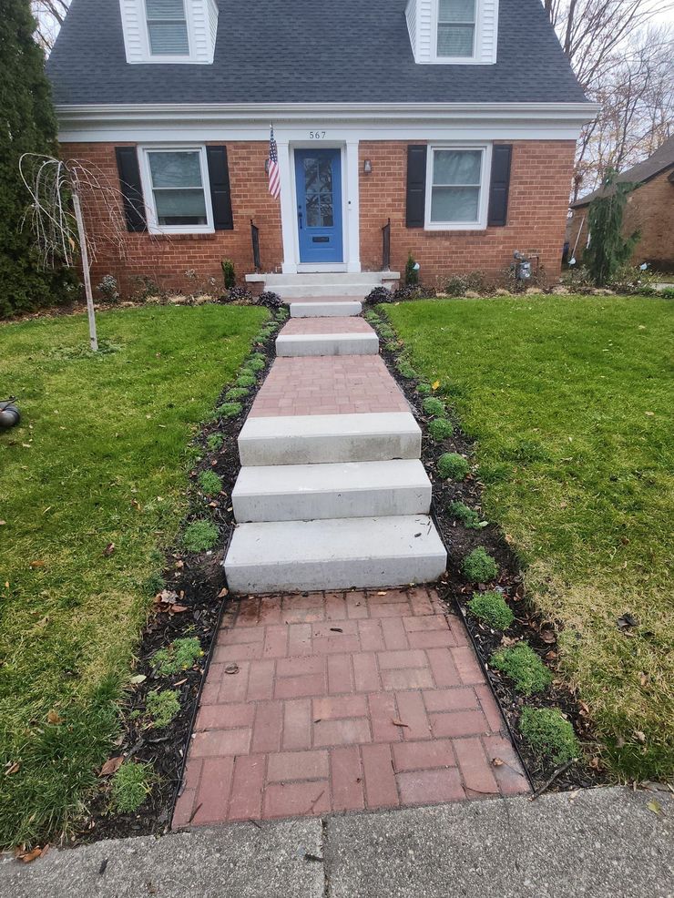 A brick walkway leading to a brick house with a blue door.