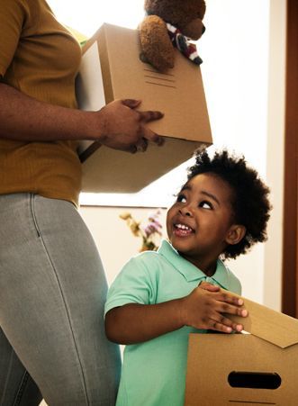 A woman is holding a cardboard box and a child is holding a teddy bear.