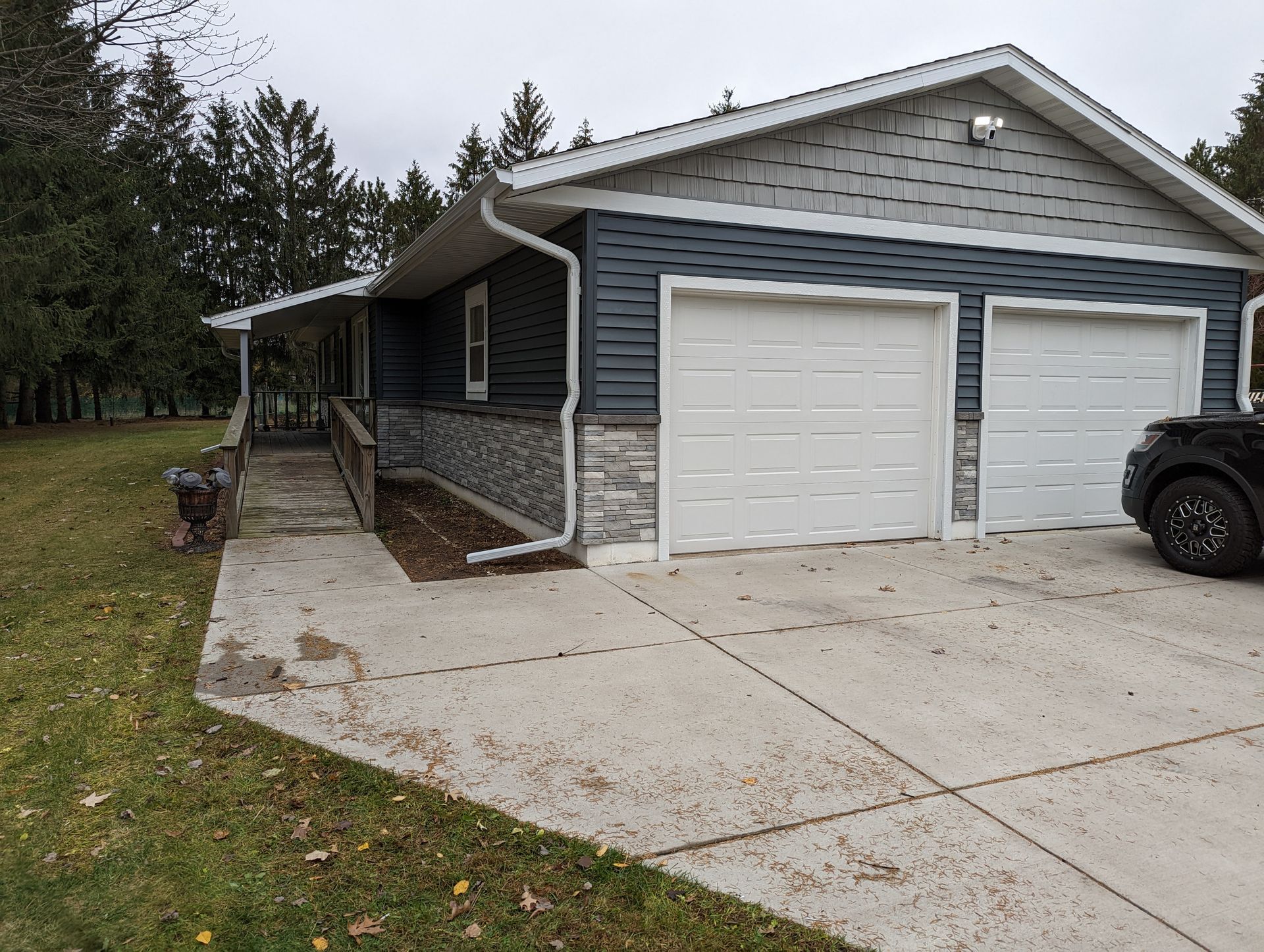 A house with two garage doors and a car parked in front of it.