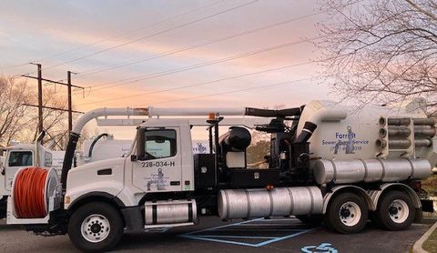 A vacuum truck is parked in a handicapped parking spot.