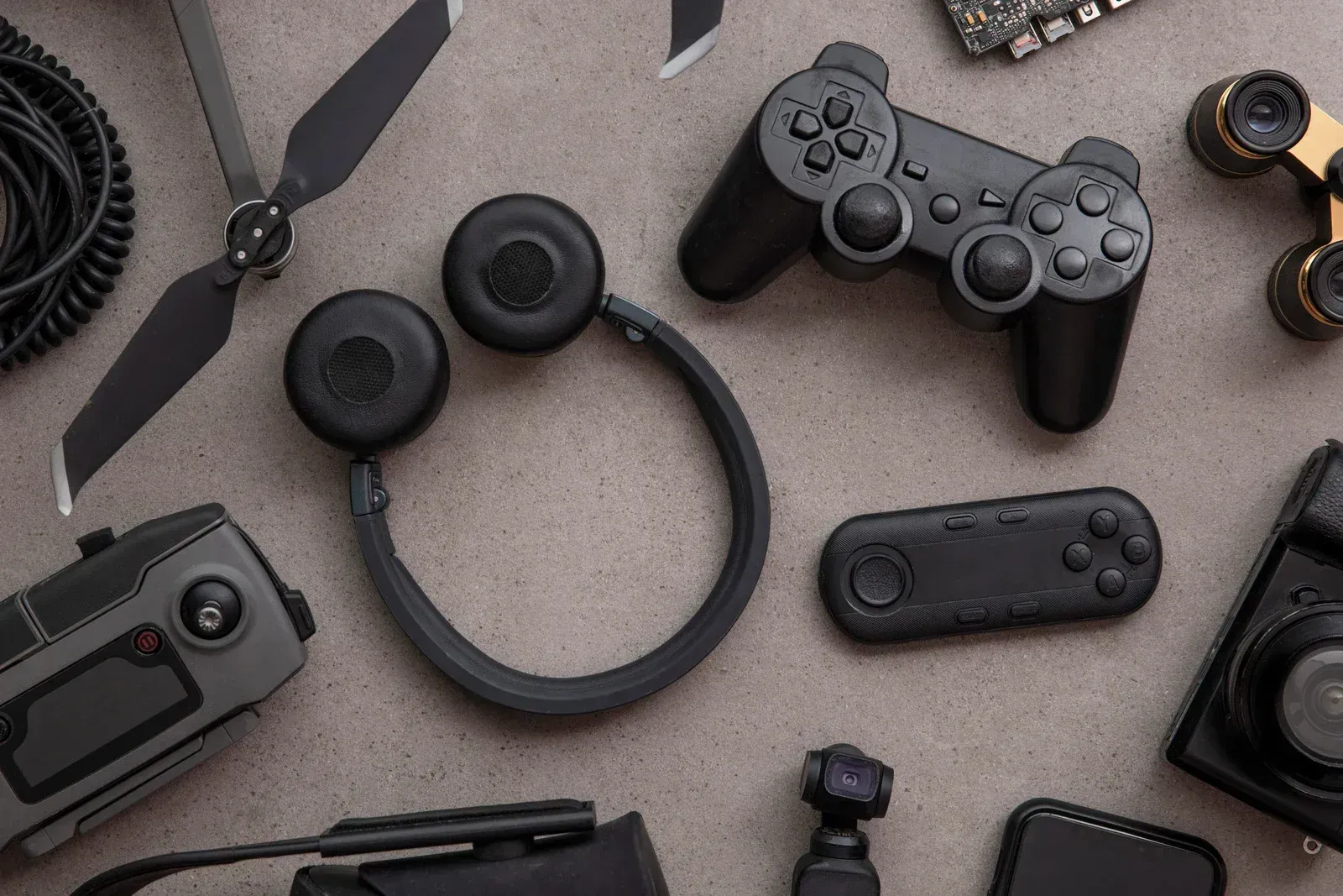 Assorted gaming accessories, including controllers, headphones, and devices, arranged on a gray background