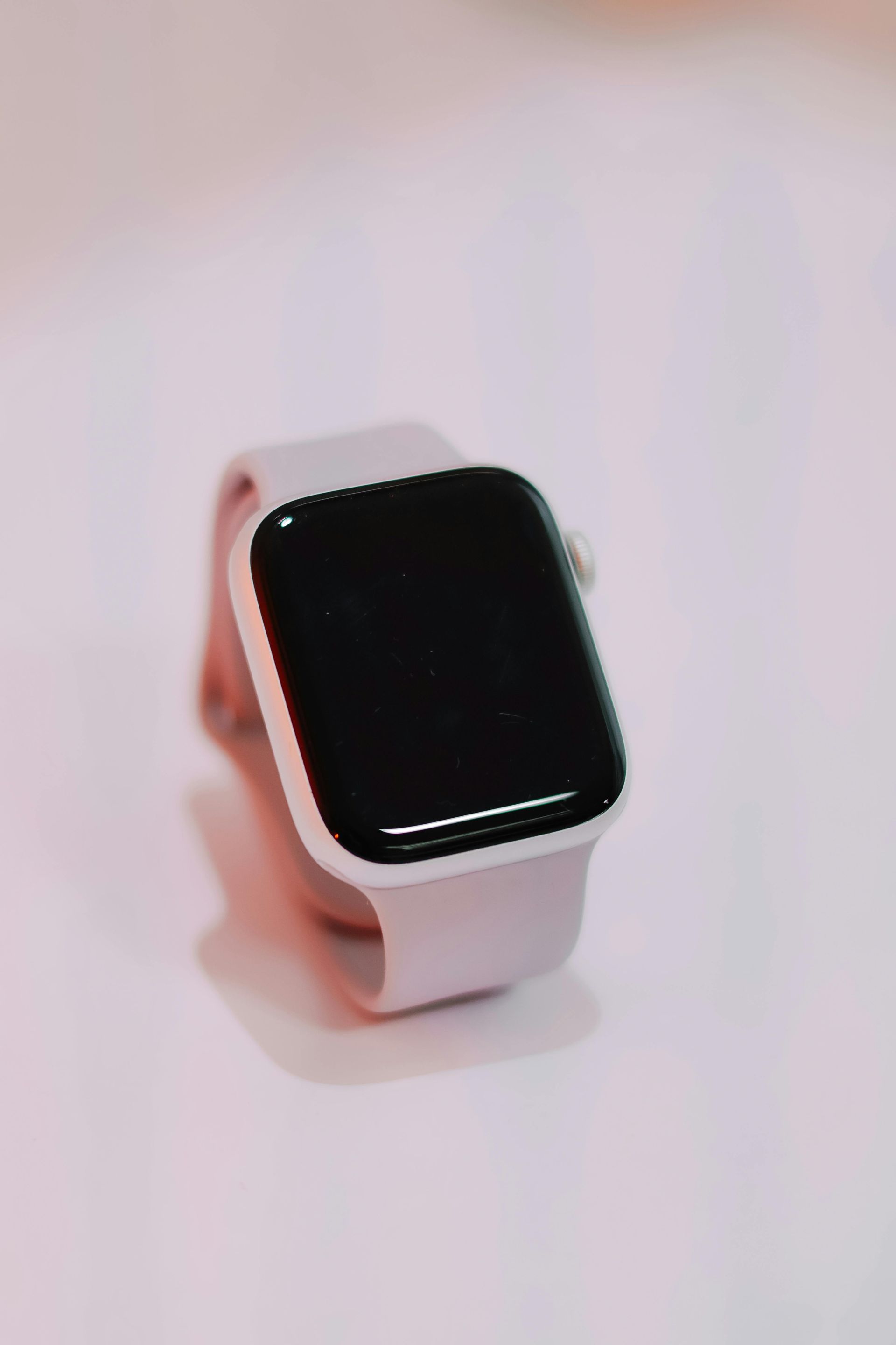Smartwatch with brown band resting on a laptop keyboard beside a trackpad