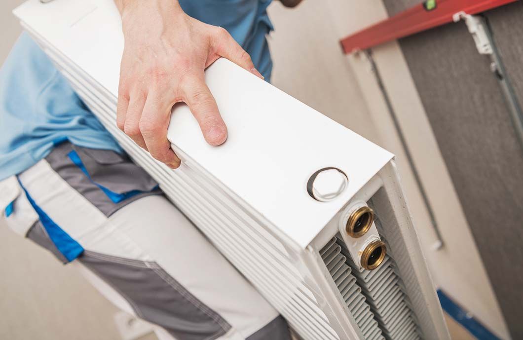 A man is holding a radiator in his hands.