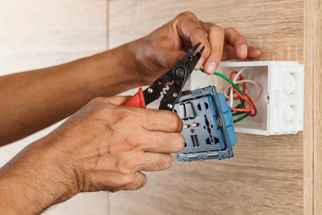 A person is working on an electrical box on a wall.