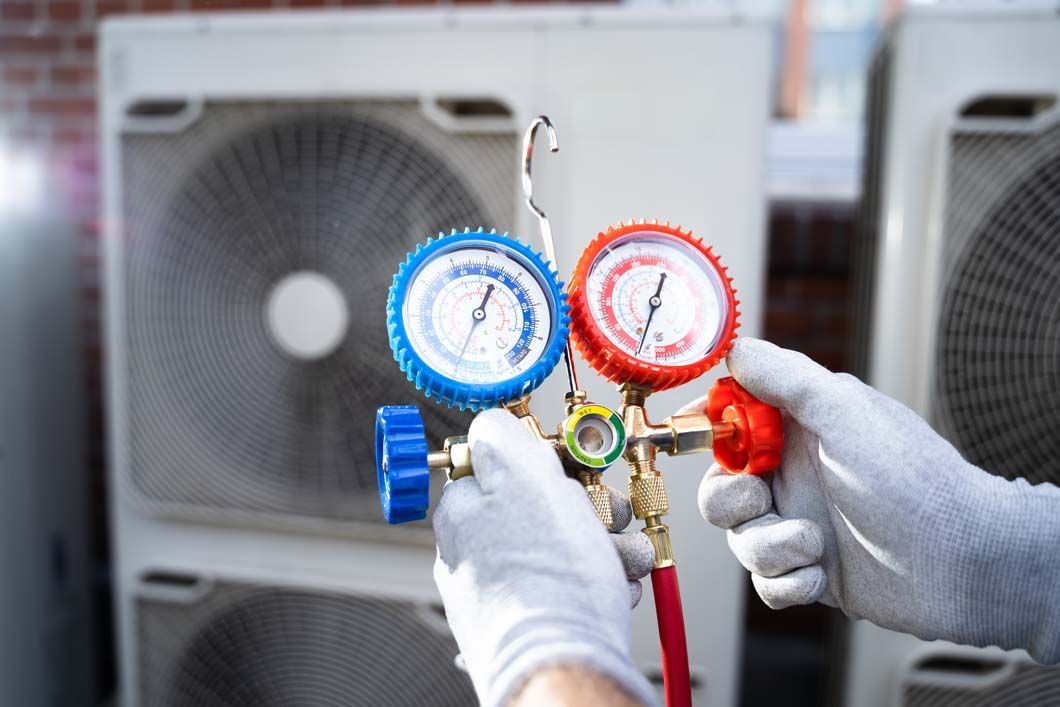 A person is holding a couple of gauges in front of an air conditioner.