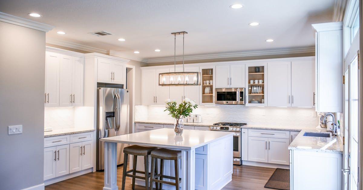 A kitchen with white cabinets , stainless steel appliances , and a large island.