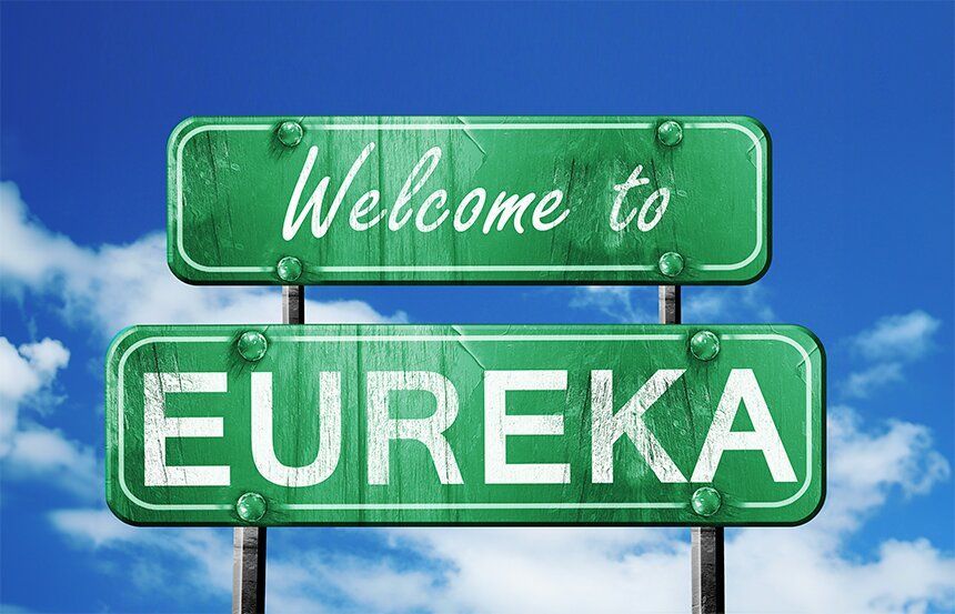 A green street sign that says welcome to eureka