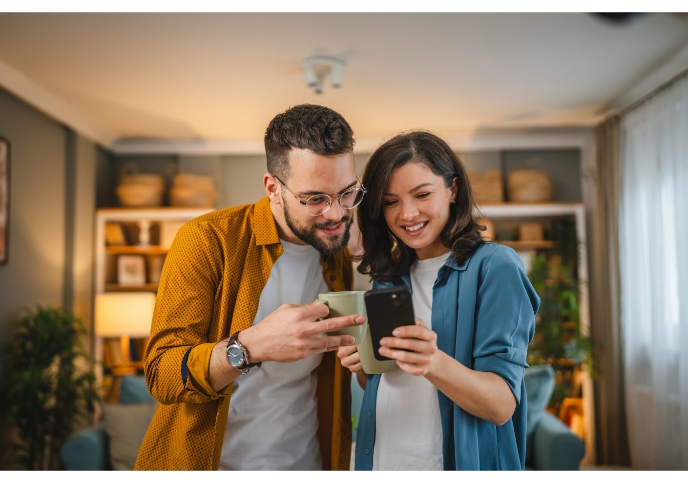 A man and a woman are looking at a cell phone together in a living room.
