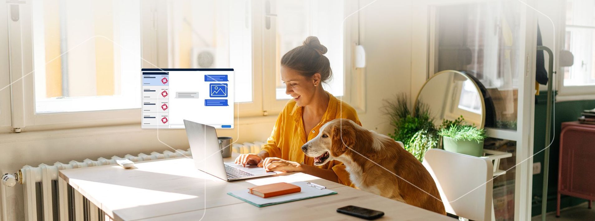 A woman is sitting at a desk with a laptop and a dog.