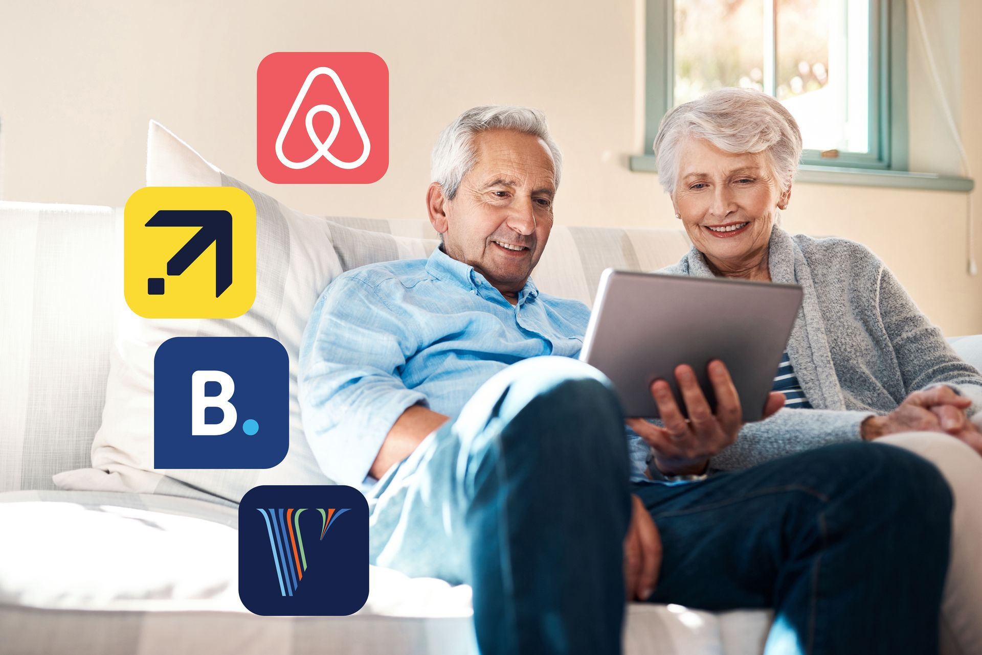 An elderly couple is sitting on a couch looking at a tablet.