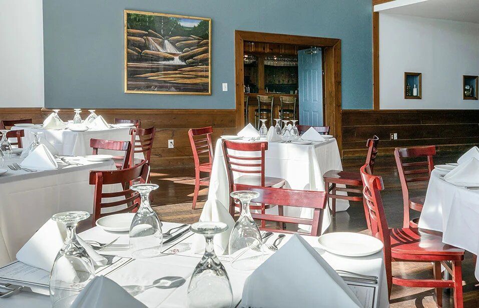A dining room with tables and chairs and a picture on the wall
