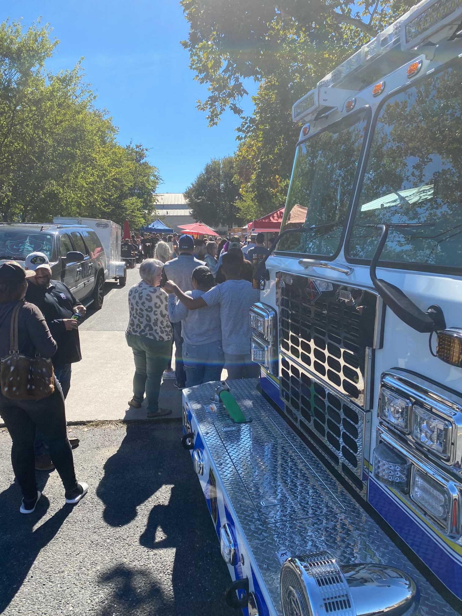 A group of people are standing in front of a large white fire truck.