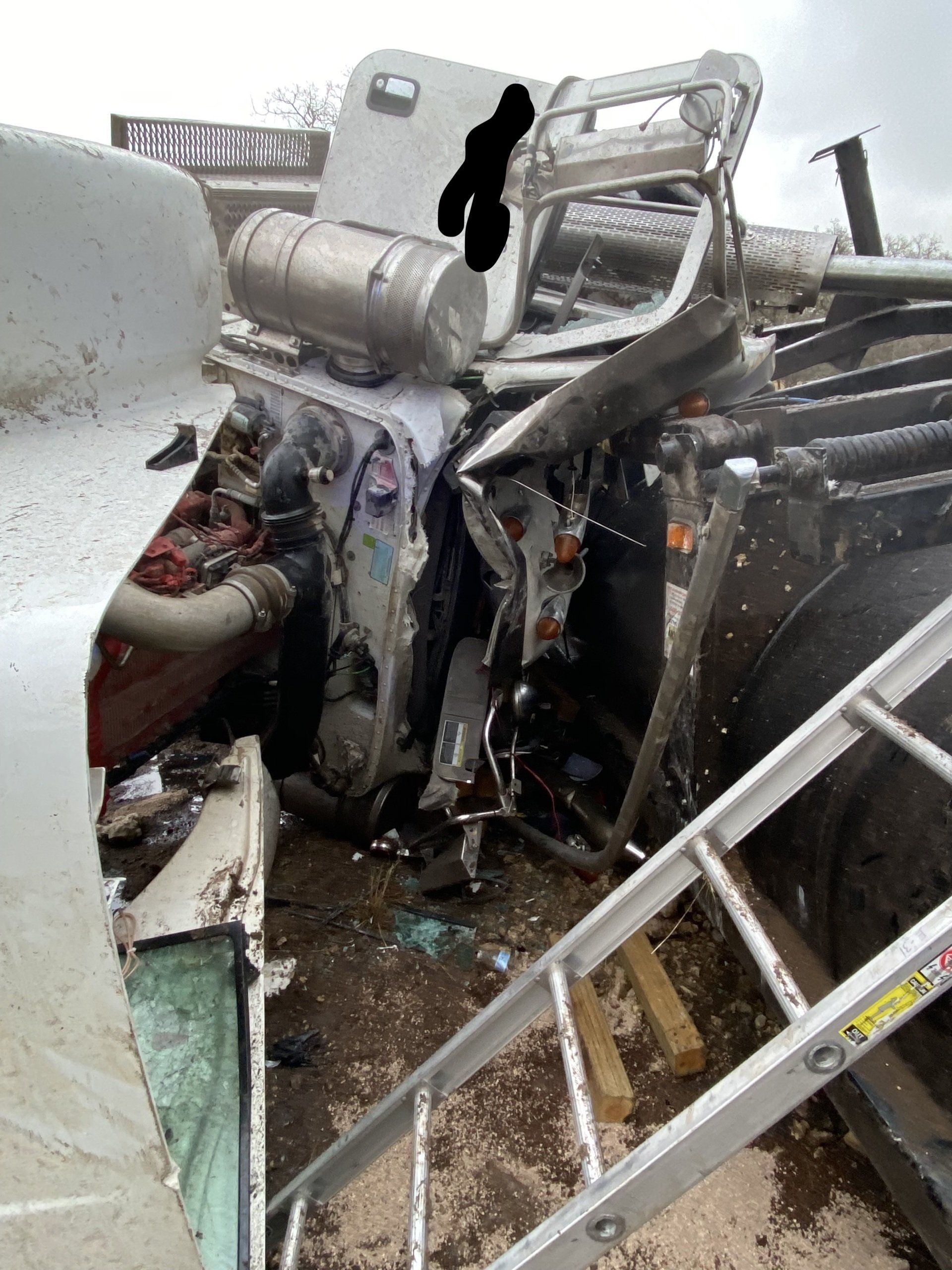 A ladder is sitting next to a wrecked truck.