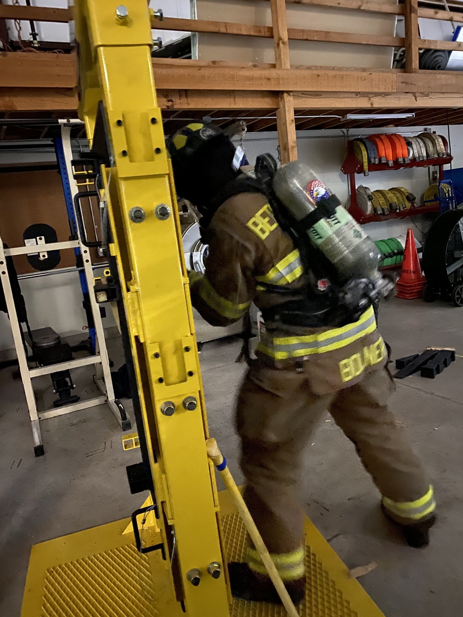A fireman wearing a helmet and oxygen tank is training on breaching a door.