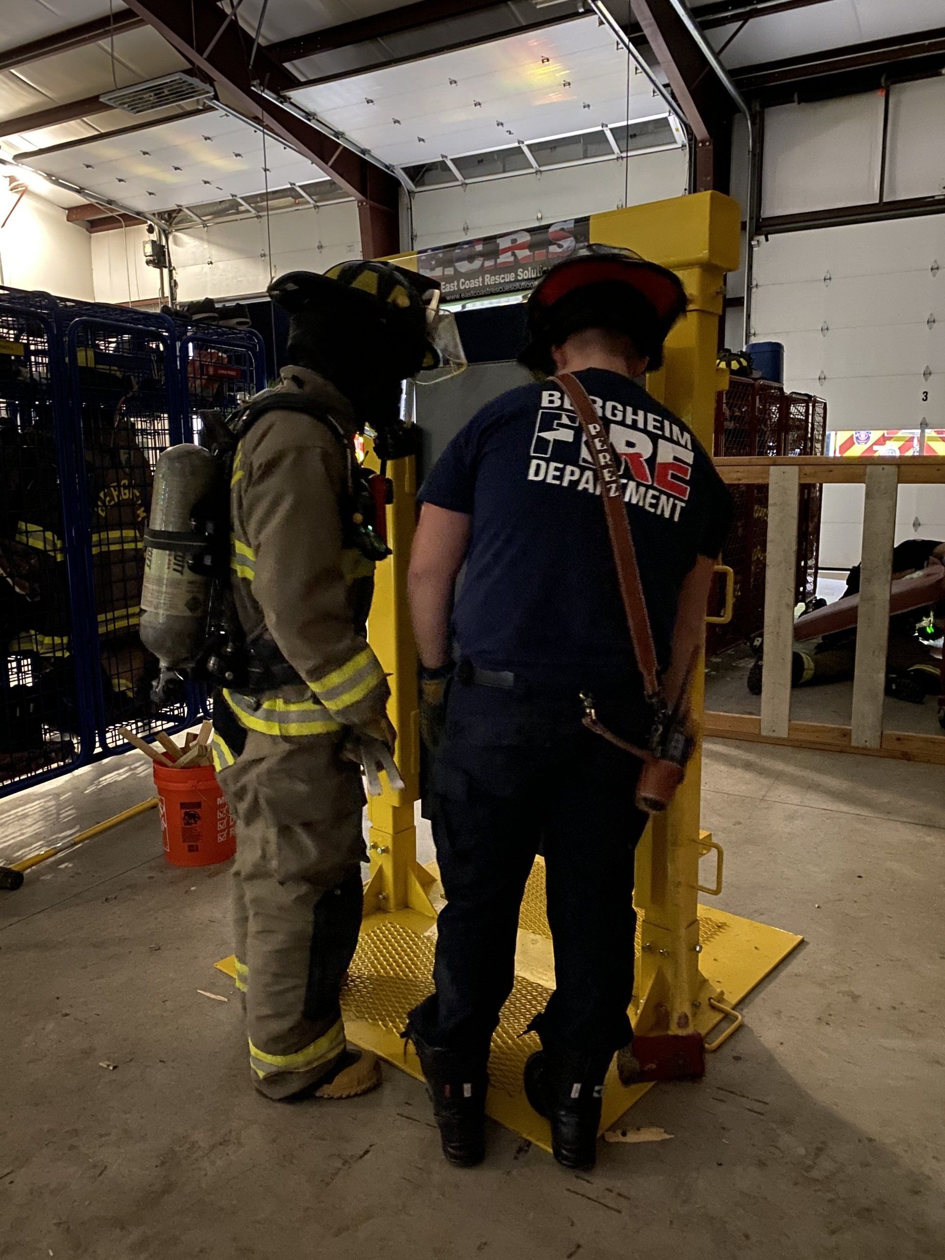 A fireman wearing a helmet and oxygen tank is training on how to breach a door.