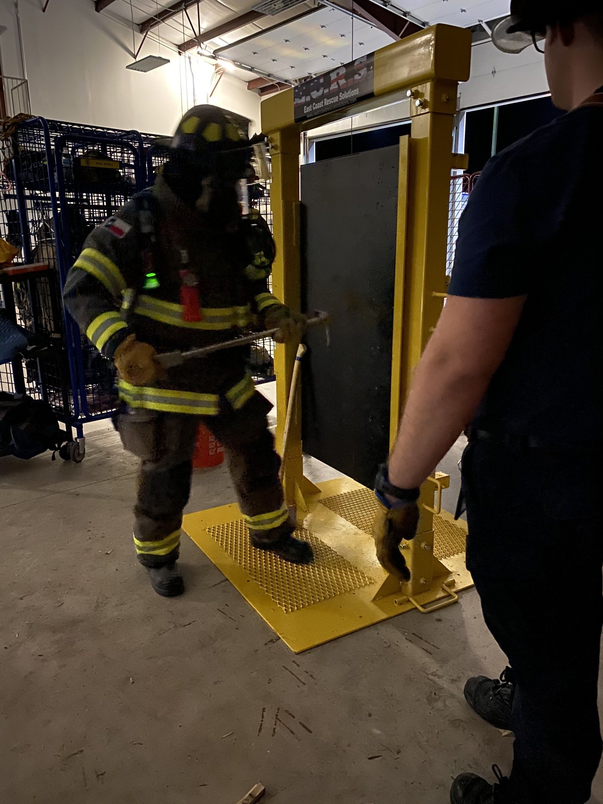 A fireman wearing a helmet and oxygen tank is training on how to breach a door.