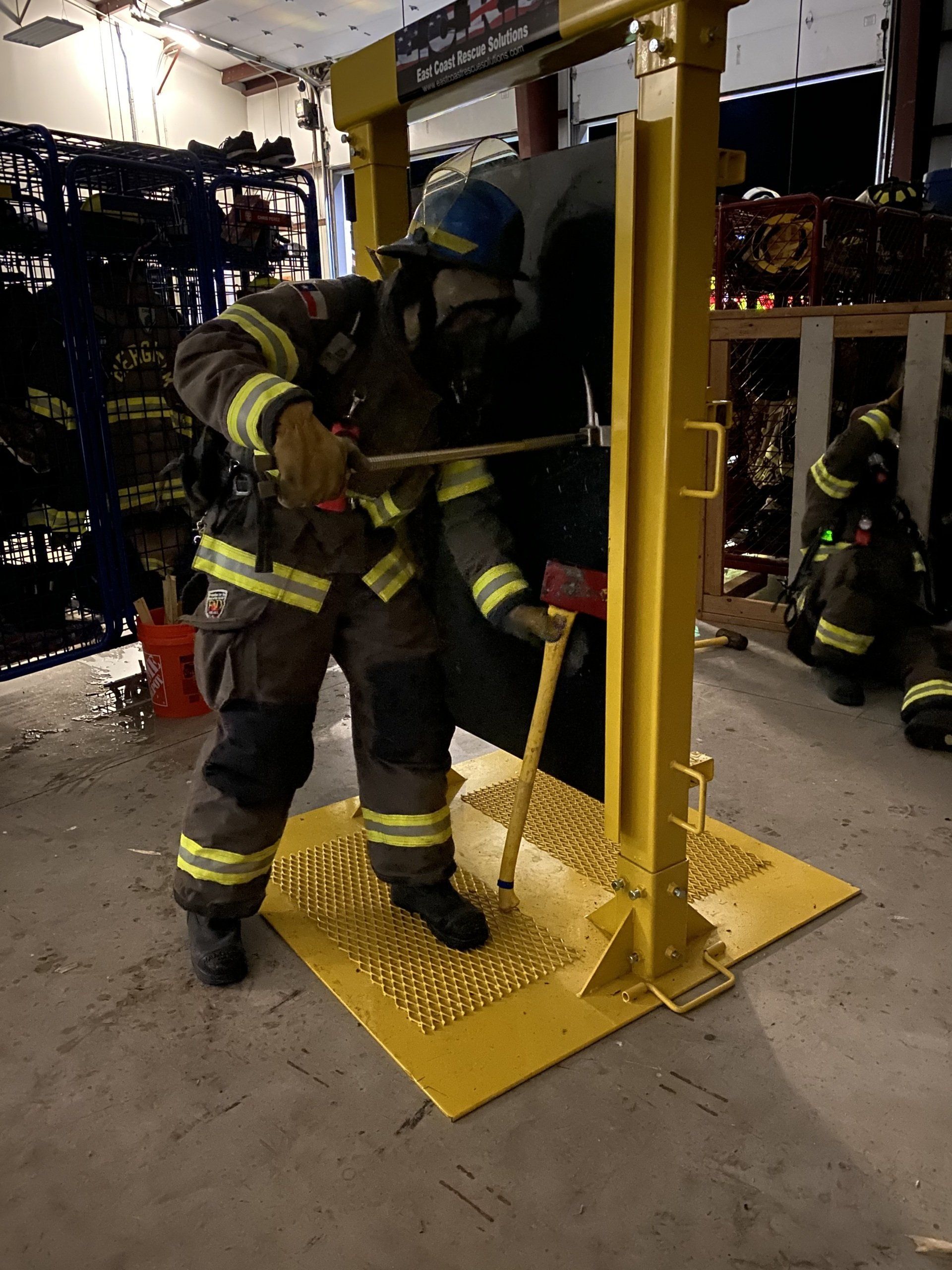 A fireman wearing a helmet and oxygen tank is training on how to breach a door.