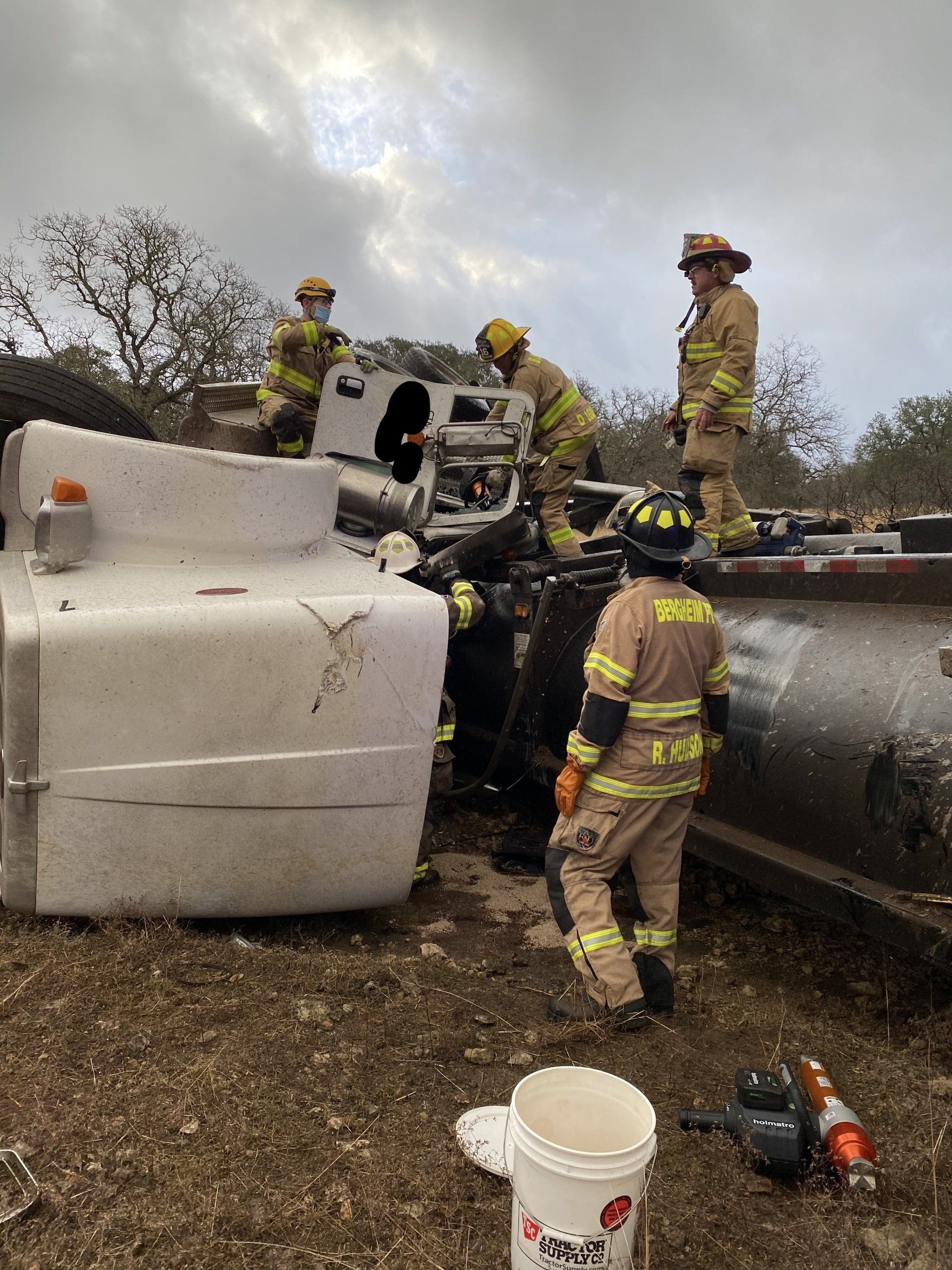 A group of firefighters are working on a truck that has flipped over.