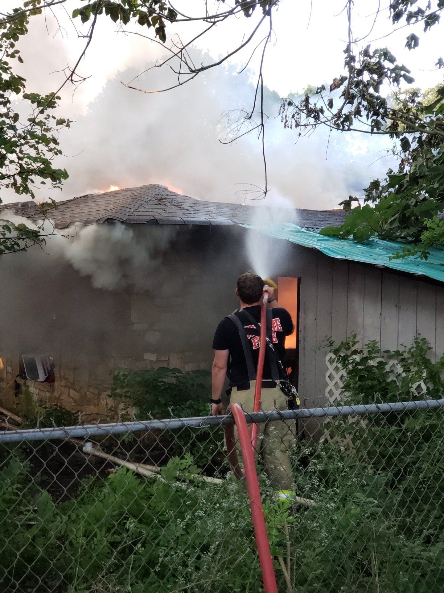 A firefighter is spraying water on a house fire.