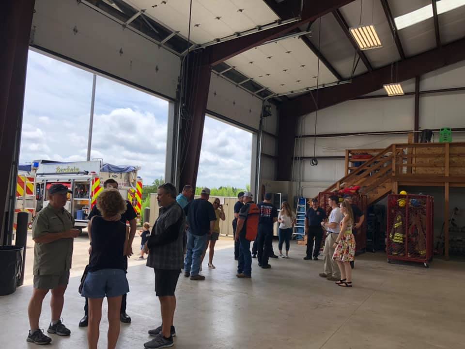 A group of people are standing in a fire station bay.