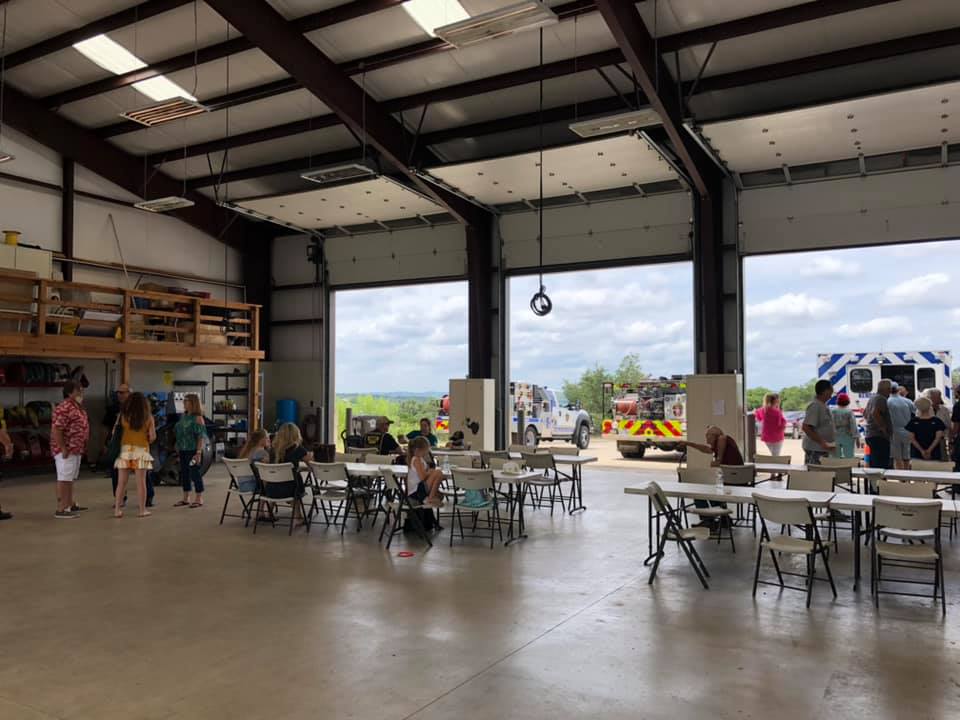 A group of people are sitting at tables in a fire station.
