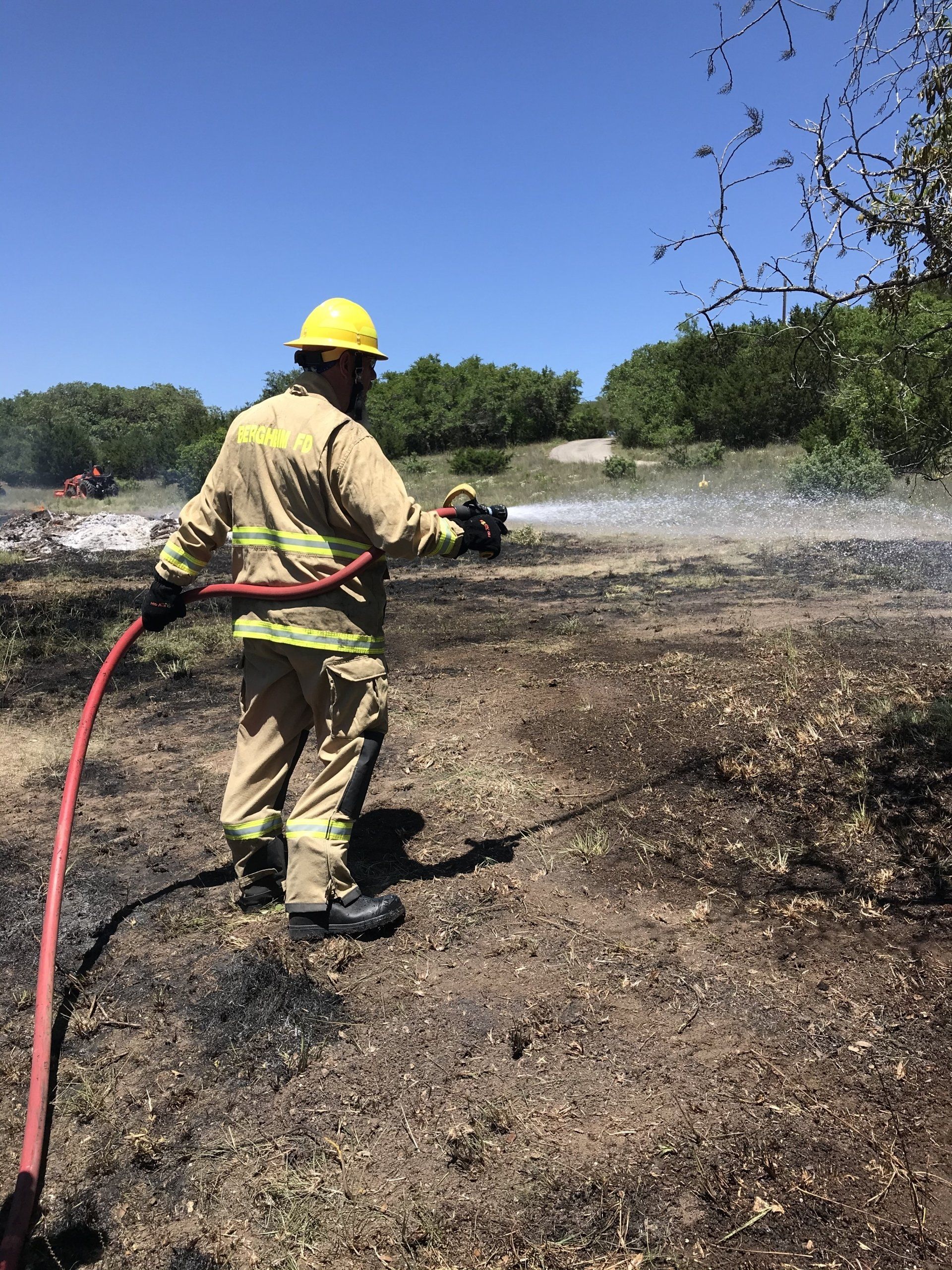 A firefighter is spraying water from a hose in a field.