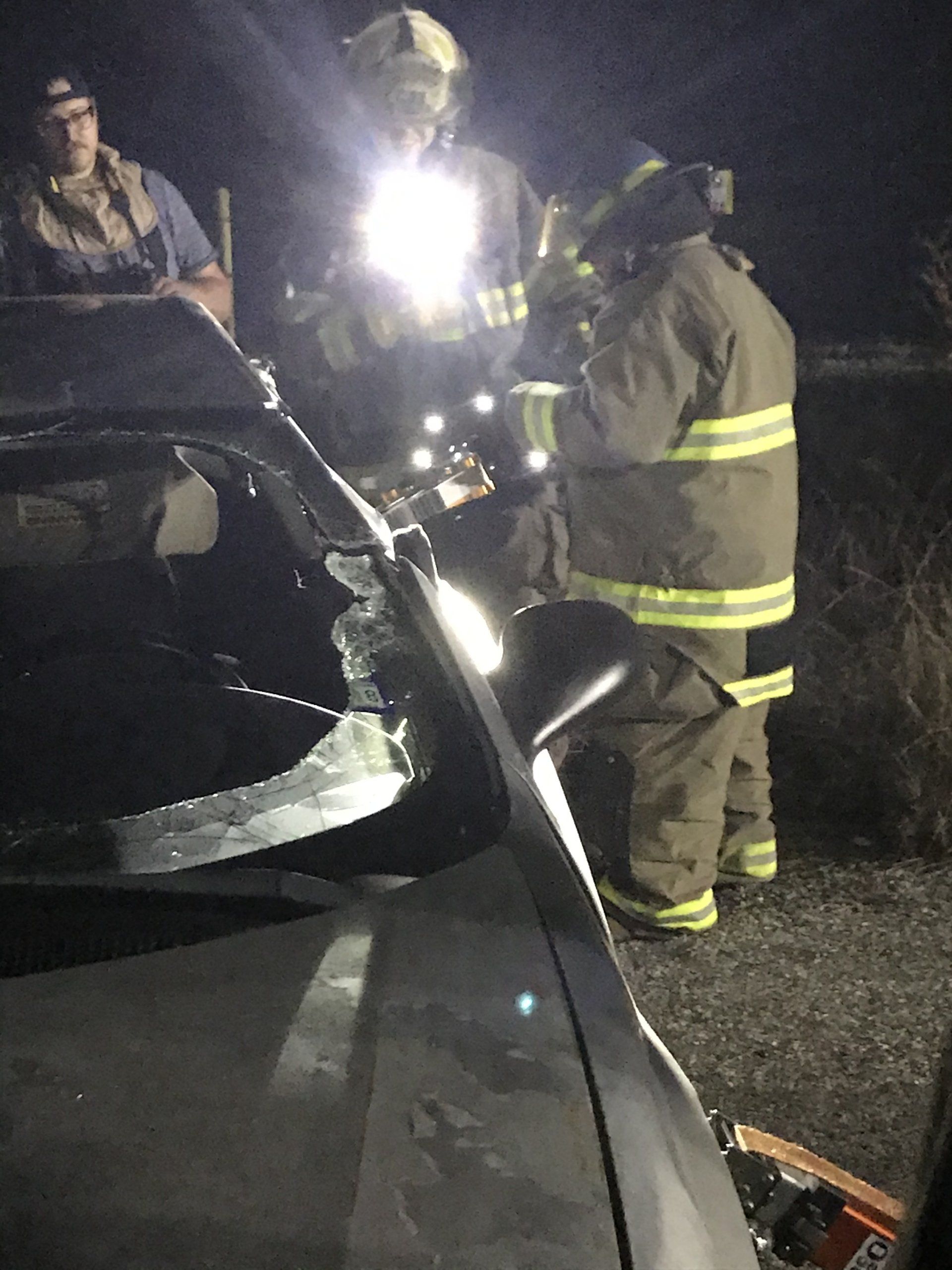 A group of firefighters are standing around a car during a training exercise.