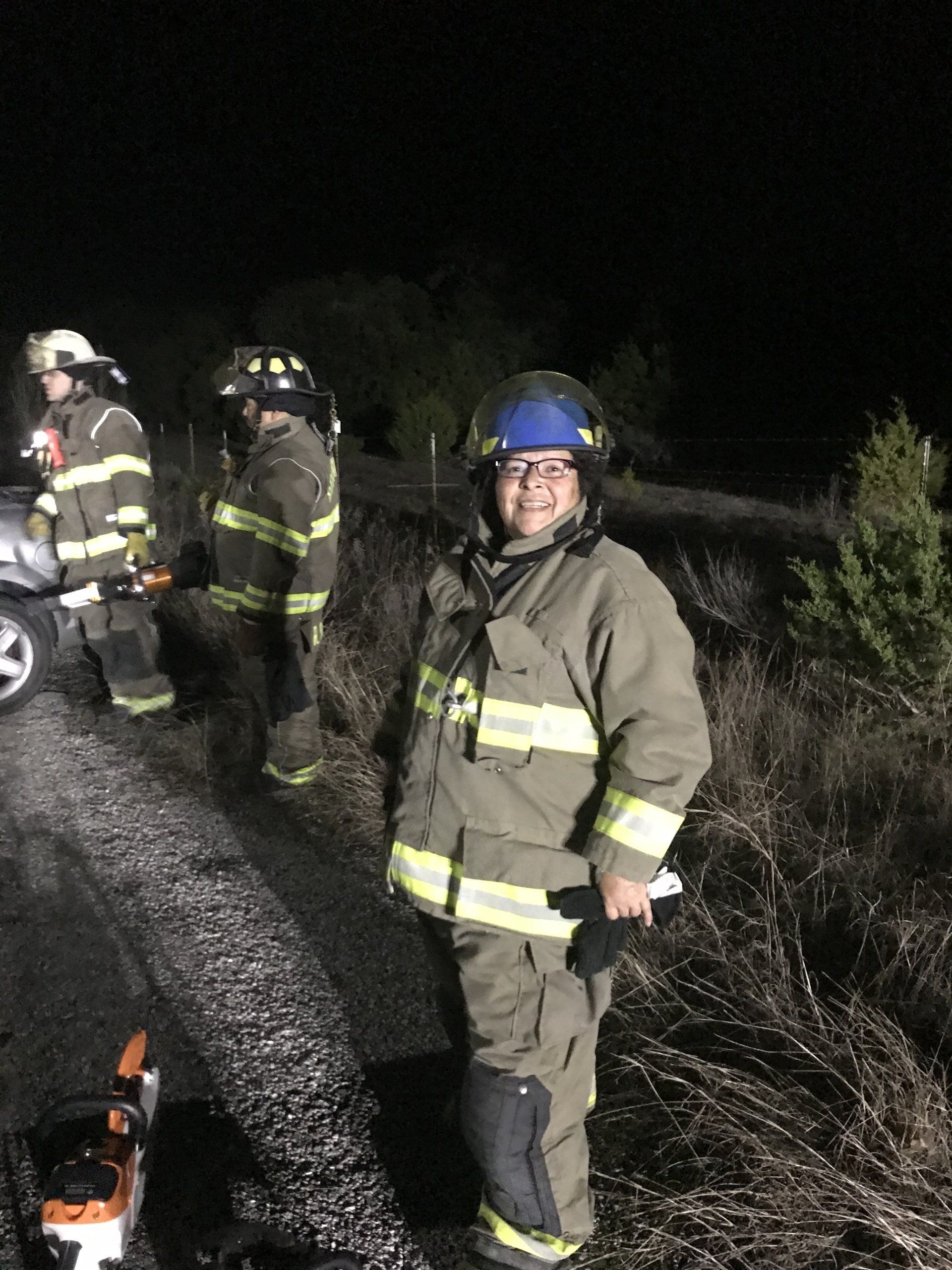 A group of firefighters are standing around a car during a training exercise.