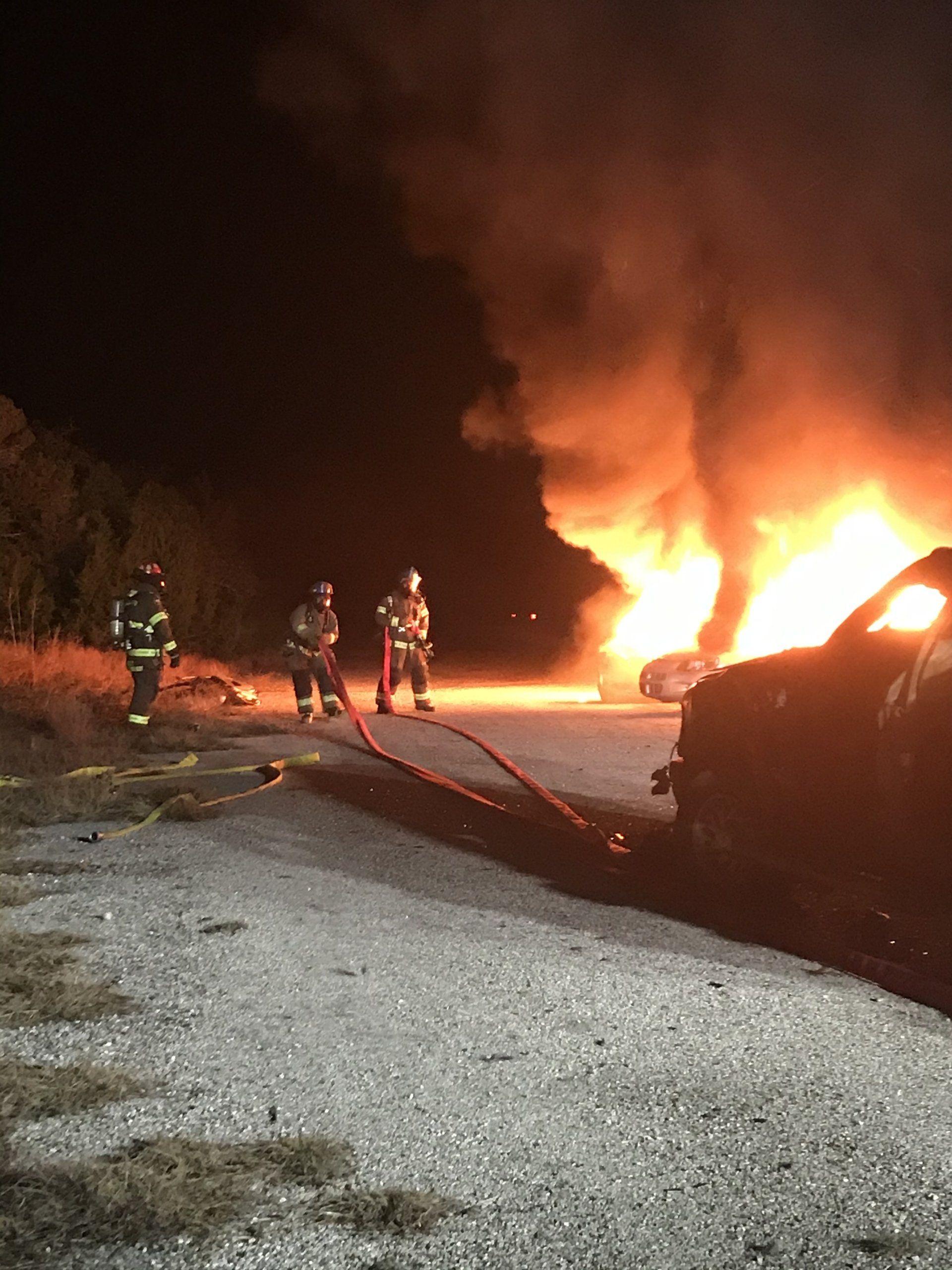 A group of fire fighters are fighting a vehicle fire. 