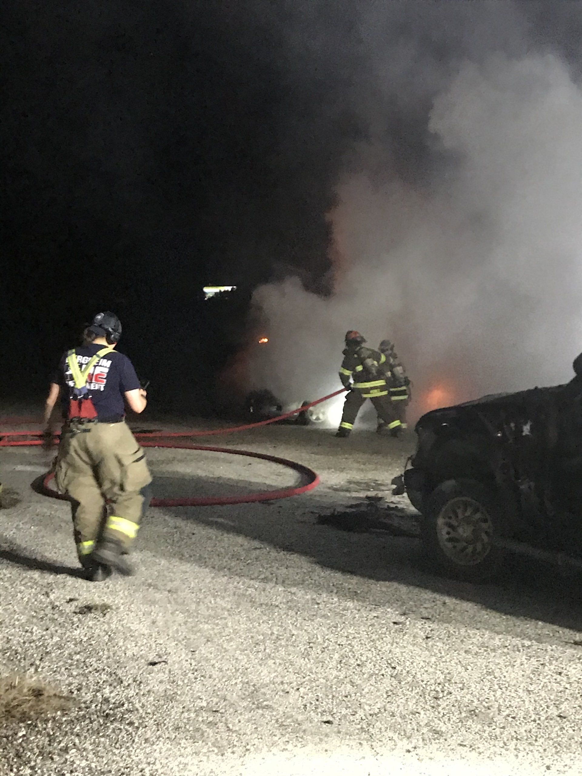 A group of firefighters are fighting a vehicle fire.