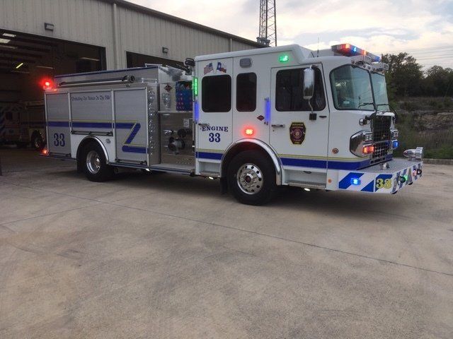 A white and blue fire truck with the number parked in front of a fire station