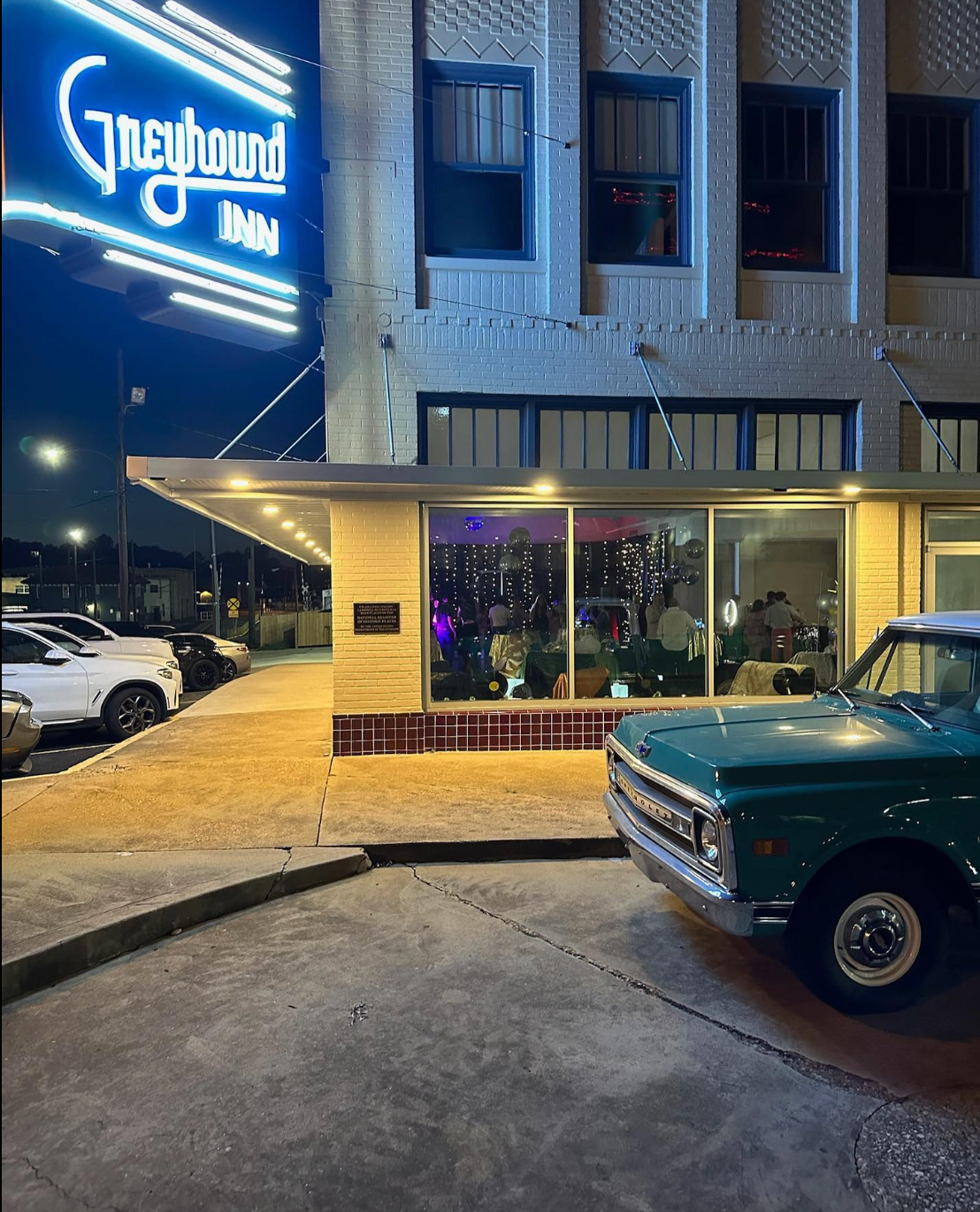 A green truck is parked in front of the greyhound motel