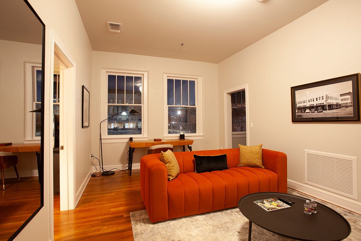 A living room with an orange couch and a black coffee table